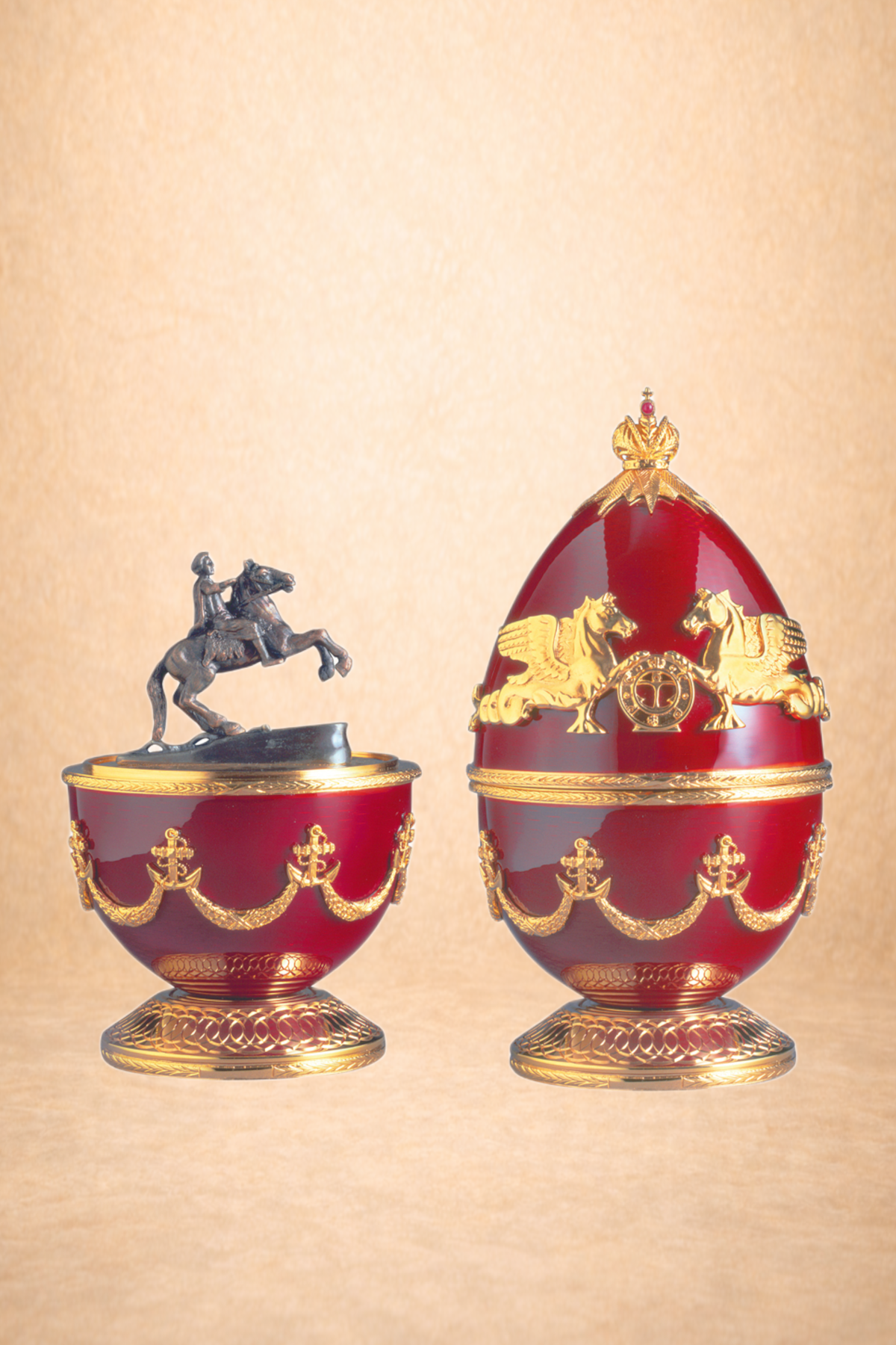 Decorative red and gold oval-shaped containers with ornate detailing, topped with a crown and winged lion motifs; one container features a small statue of a person riding a horse.