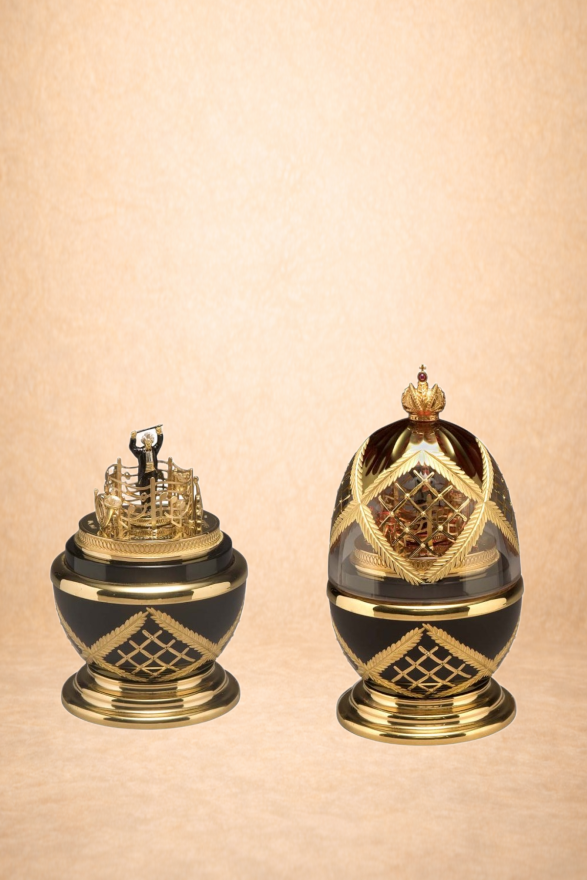 Two ornate black and gold decorative objects with intricate designs and crowns, set against a beige background.