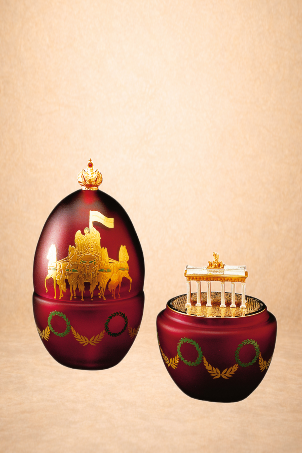 Decorative red vessels with gold details of ancient Greek themes, featuring a chariot with horses and a structure resembling a temple.