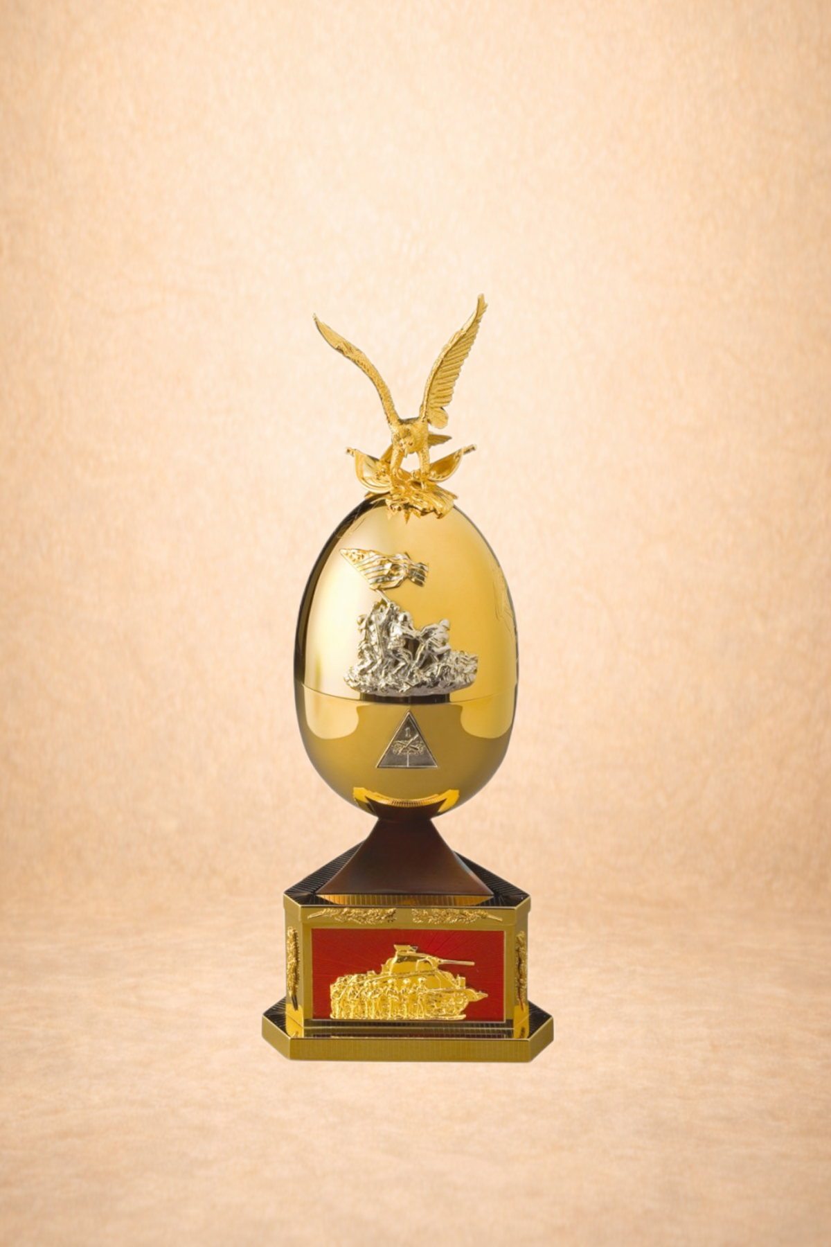 A gold trophy featuring an eagle with outstretched wings on top, a tank diagram on the middle section, and an emblem of a tank on the base, set against a beige background.
