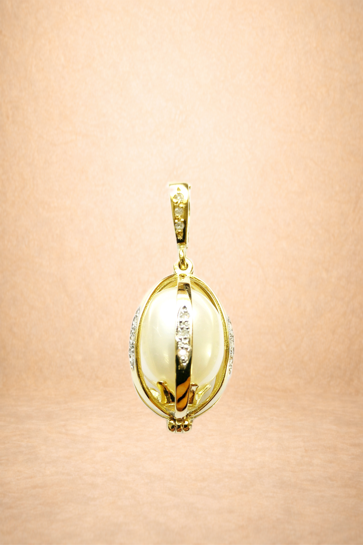 Gold pendant with a large pearl and diamond accents on a skin background.