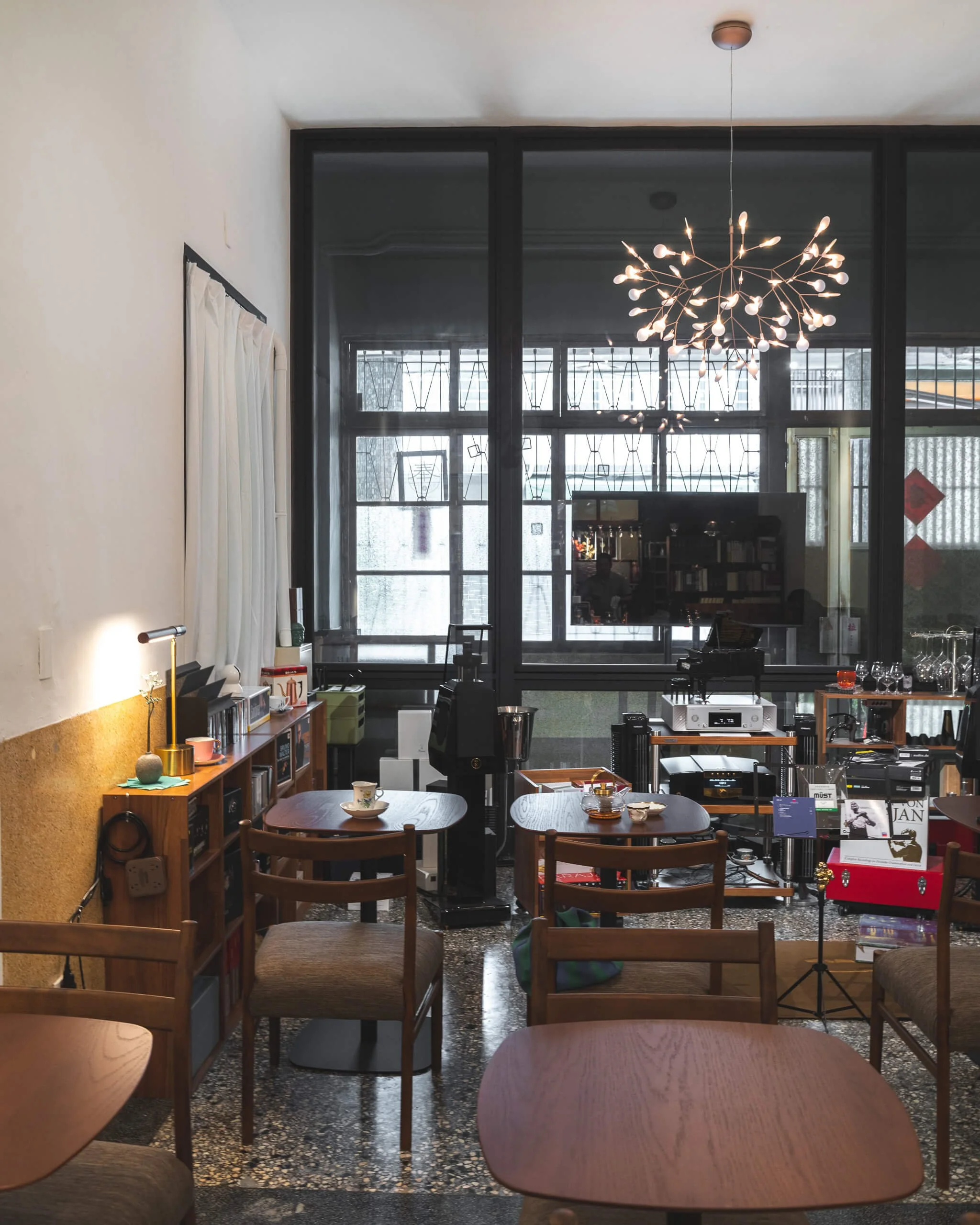 台中 Until 室內設計 Feng Cafe 奉咖啡店內全景，白色高牆與深色花窗，枝狀吊燈下為木色圓桌與座椅