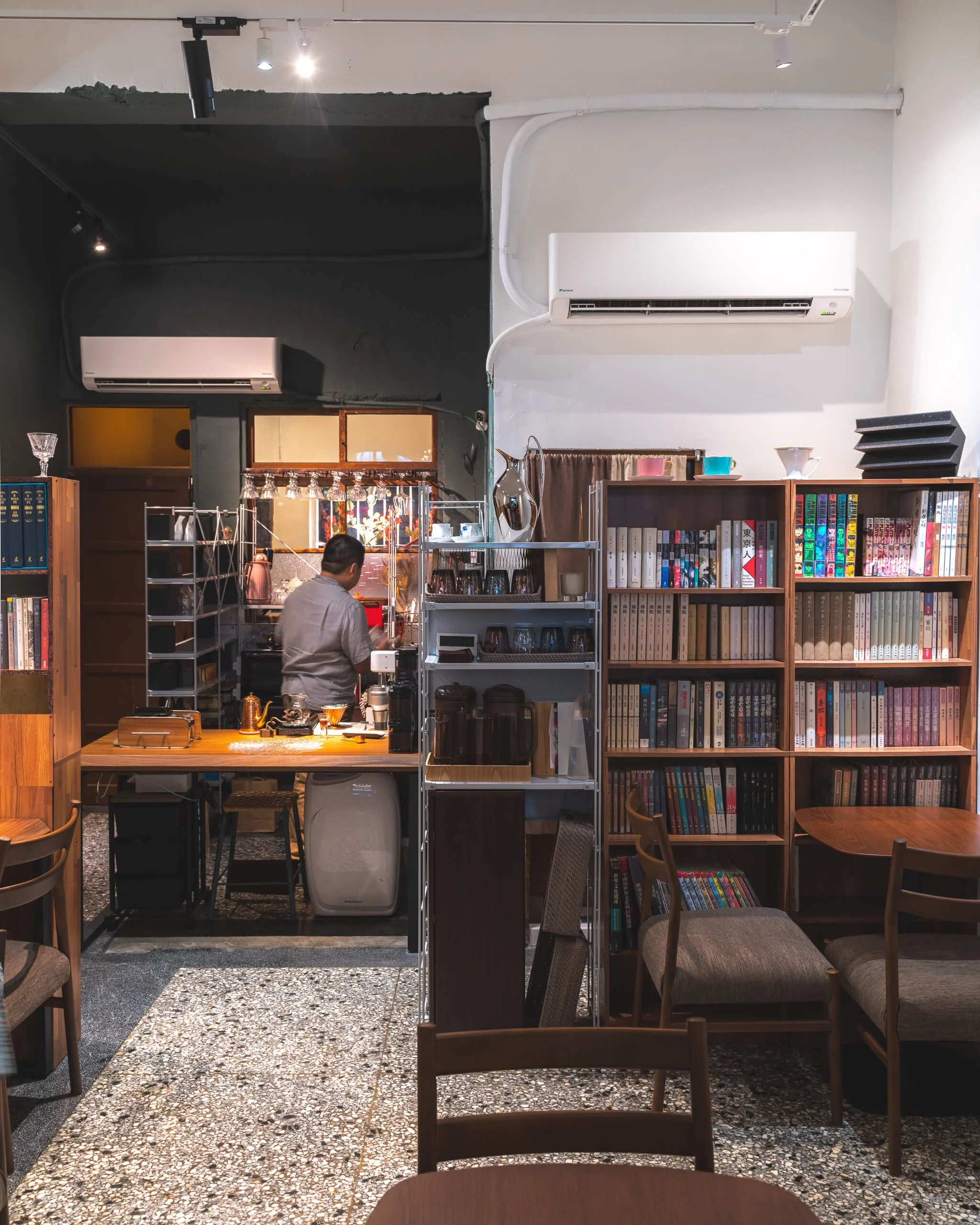 台中 Until 室內設計 Feng Cafe 奉咖啡吧檯與書架，深綠色牆面搭配木質書架、杯具展示架與木色桌椅