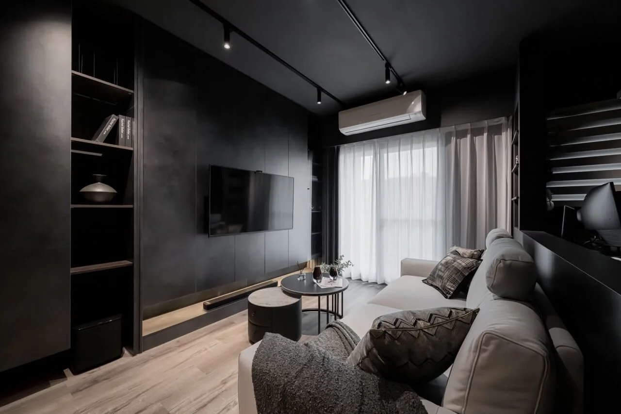 台中 Until 室內設計 H House 客廳全景，黑灰色電視牆與開放層架，淺灰色沙發與圓形邊几，窗邊配置白色紗簾