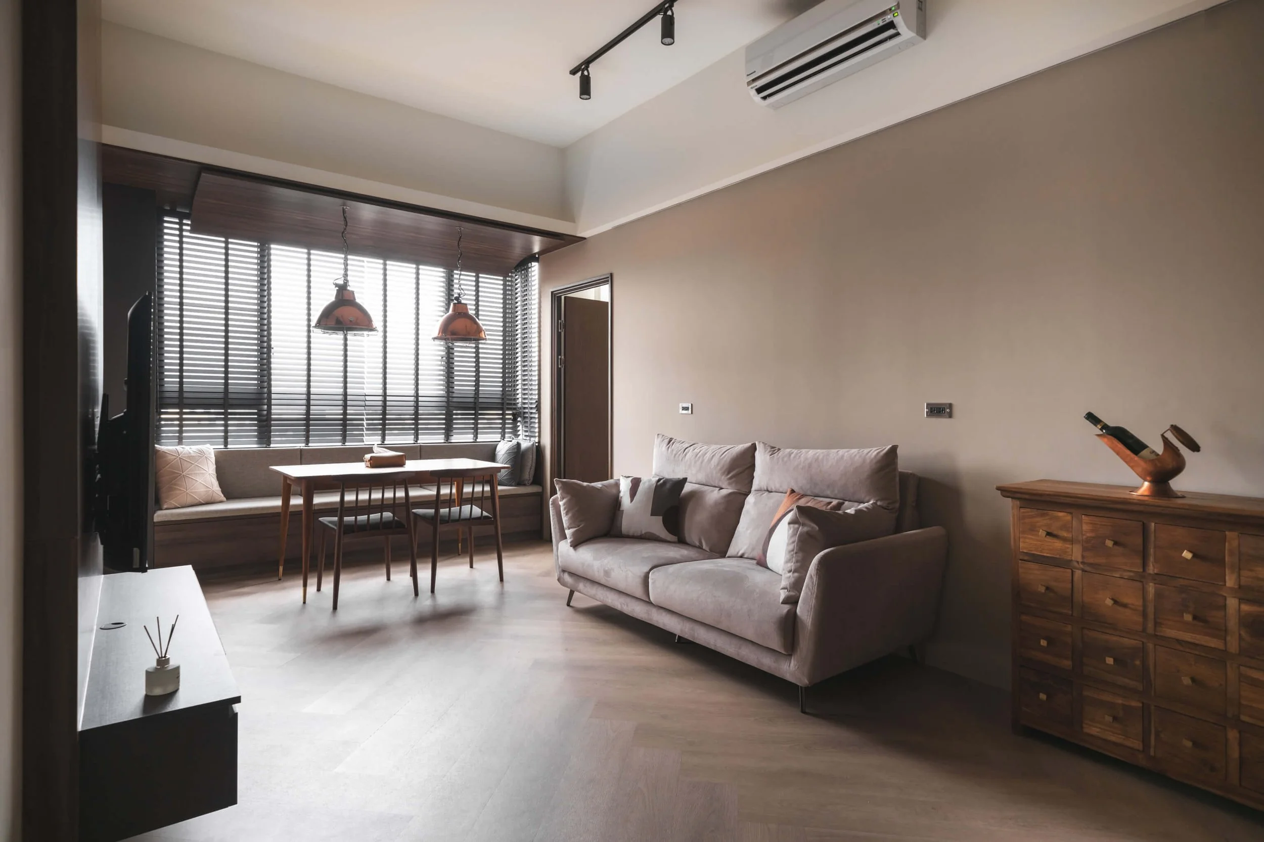 台中 Until 室內設計 P House 客餐廳全景，灰色布沙發與復古木質抽屜櫃，窗邊百葉窗下為餐桌與銅色吊燈