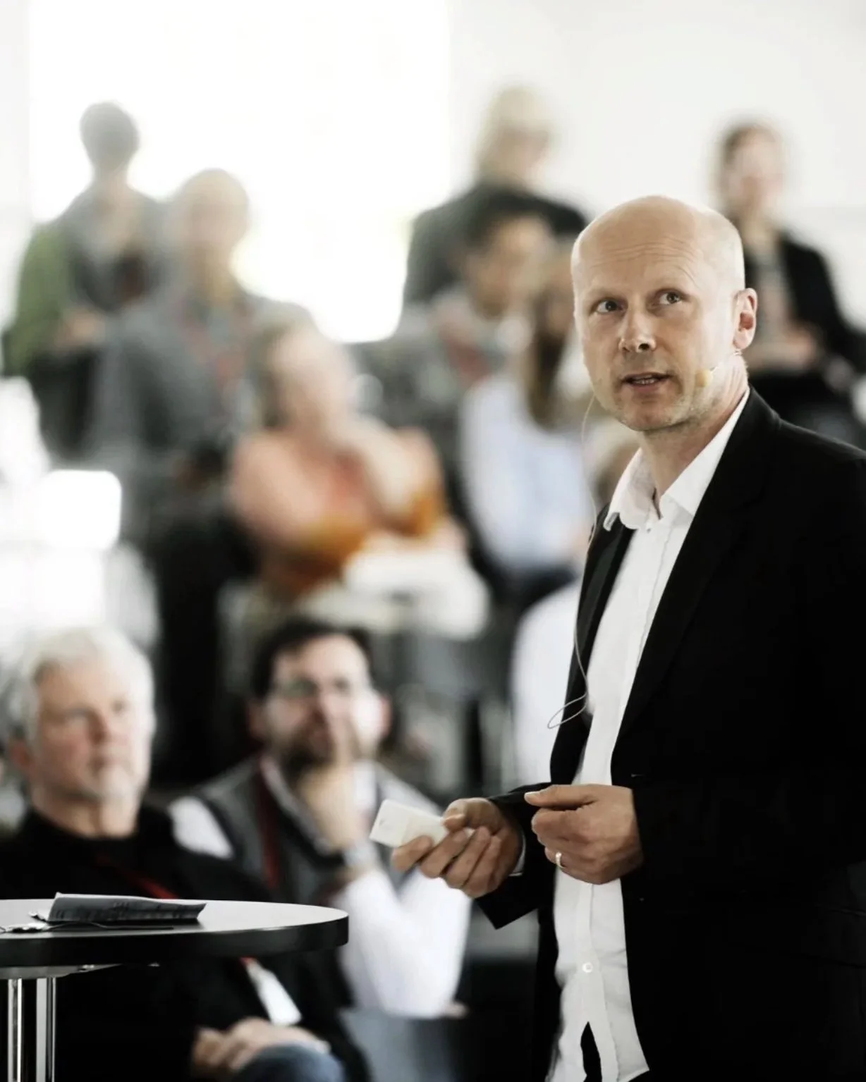 Michael Pawlyn giving a presentation to an audience, with several people listening attentively.