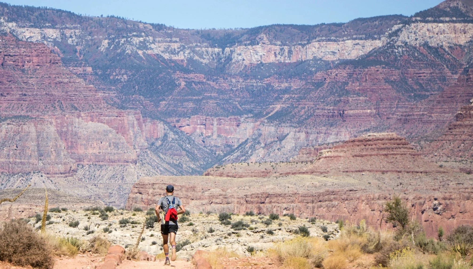 Runner moving along a red‑rock desert trail in Sedona, surrounded by layered canyon walls and sparse desert vegetation, symbolizing clarity and forward movement.