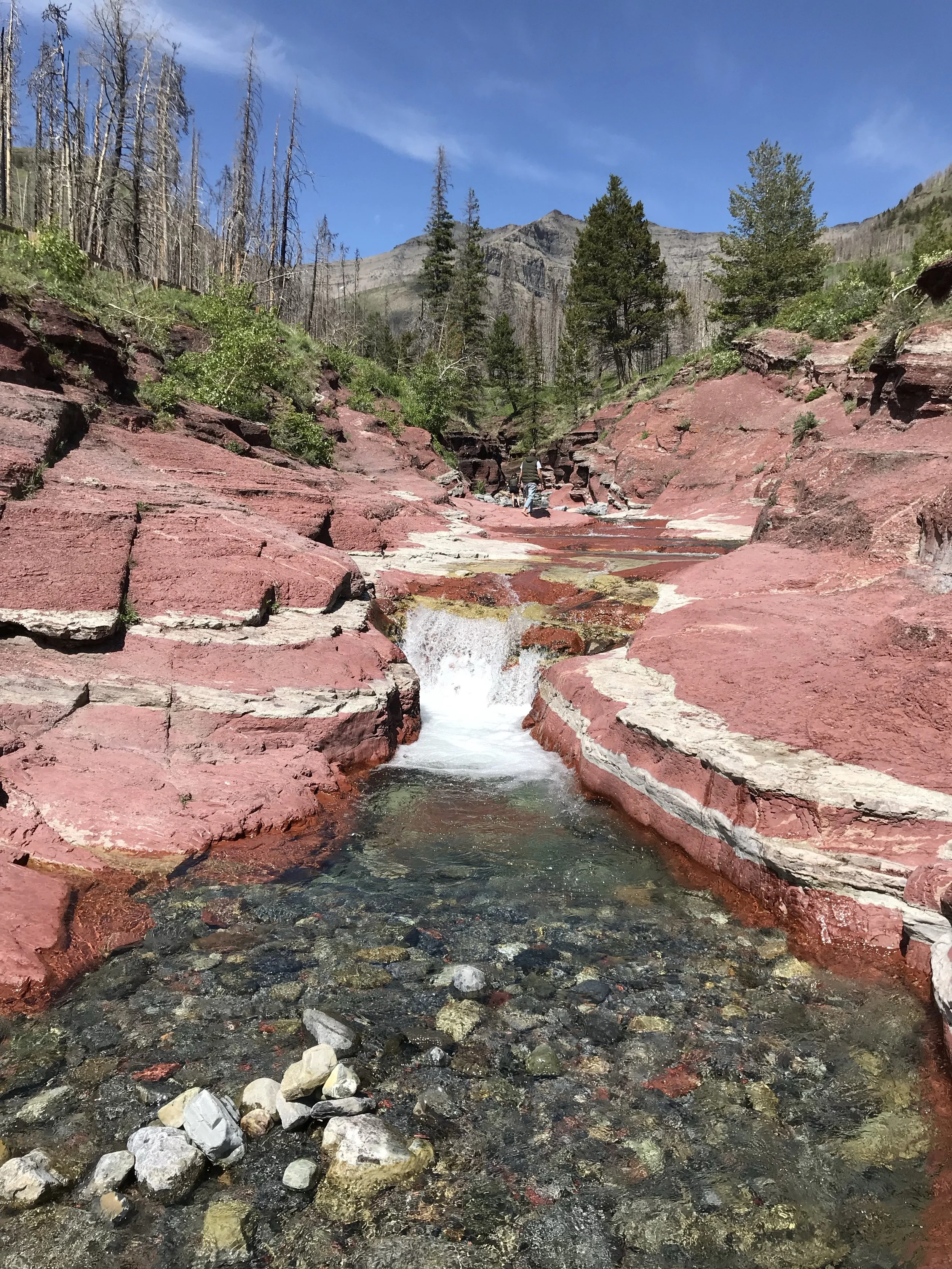 Red Rock Canyon in Waterton Lakes National Park Alberta showing vivid terracotta sandstone walls and crystal clear glacial water representing the life Desert FI readers are building toward