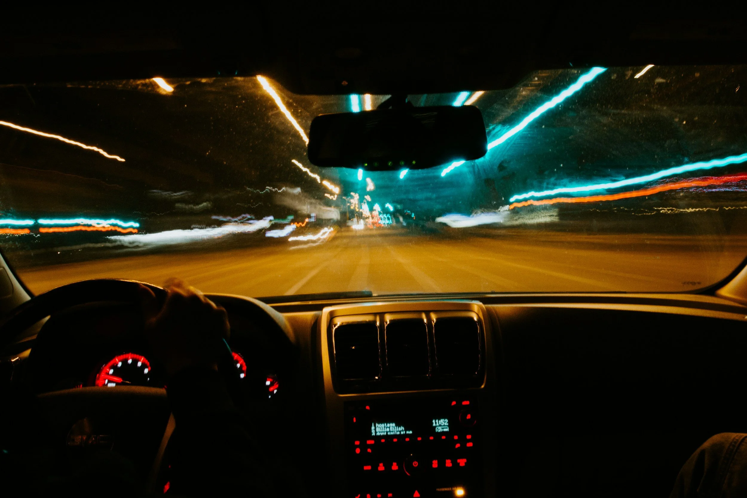 View from inside a car at night with streaking teal and white lights rushing toward the windshield representing the optimizer's mind that cannot stop running even when it's time to rest