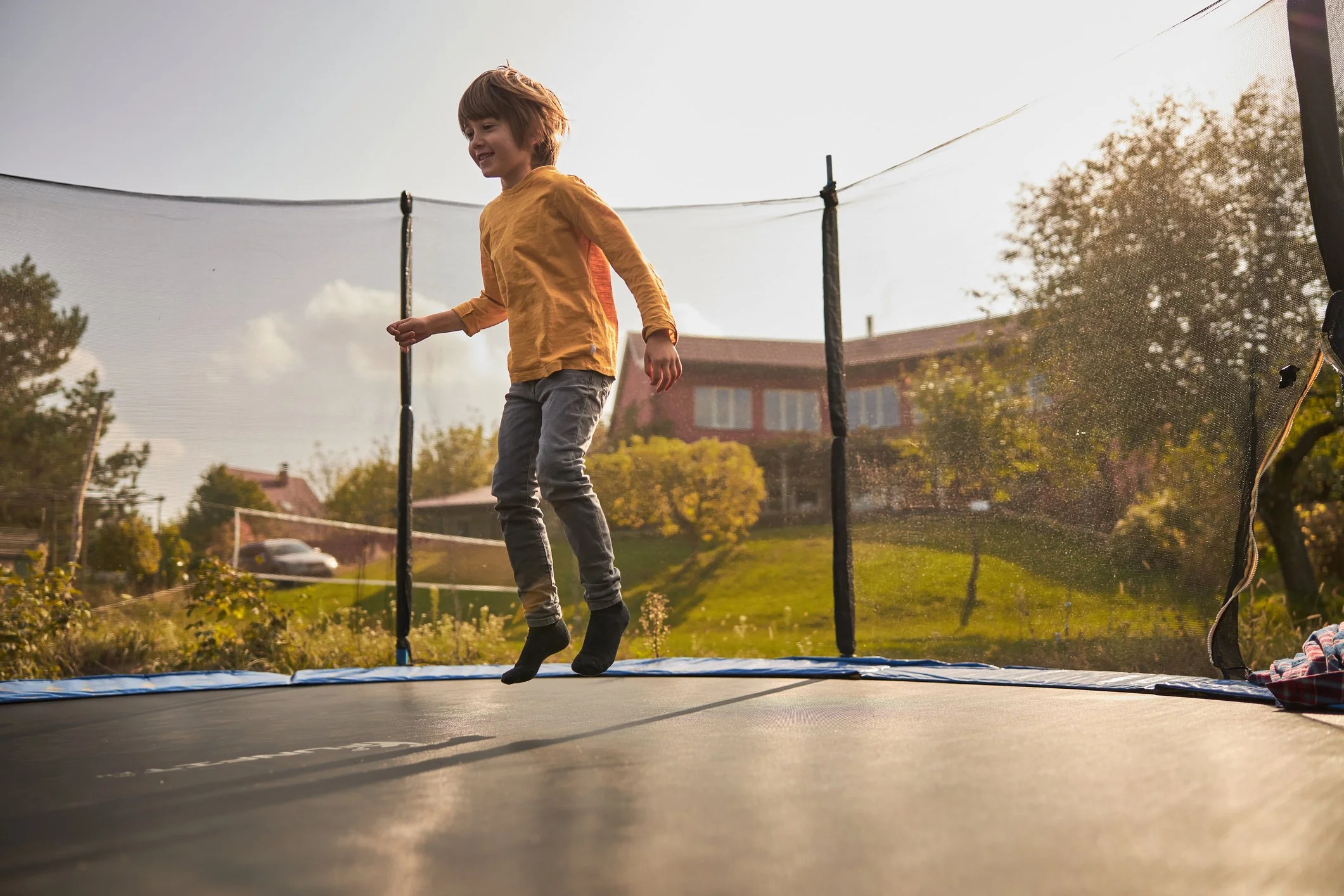 A child caught mid-jump on a backyard trampoline in warm late afternoon light, the gift I never thought to ask for, and the one I still remember forty years later.