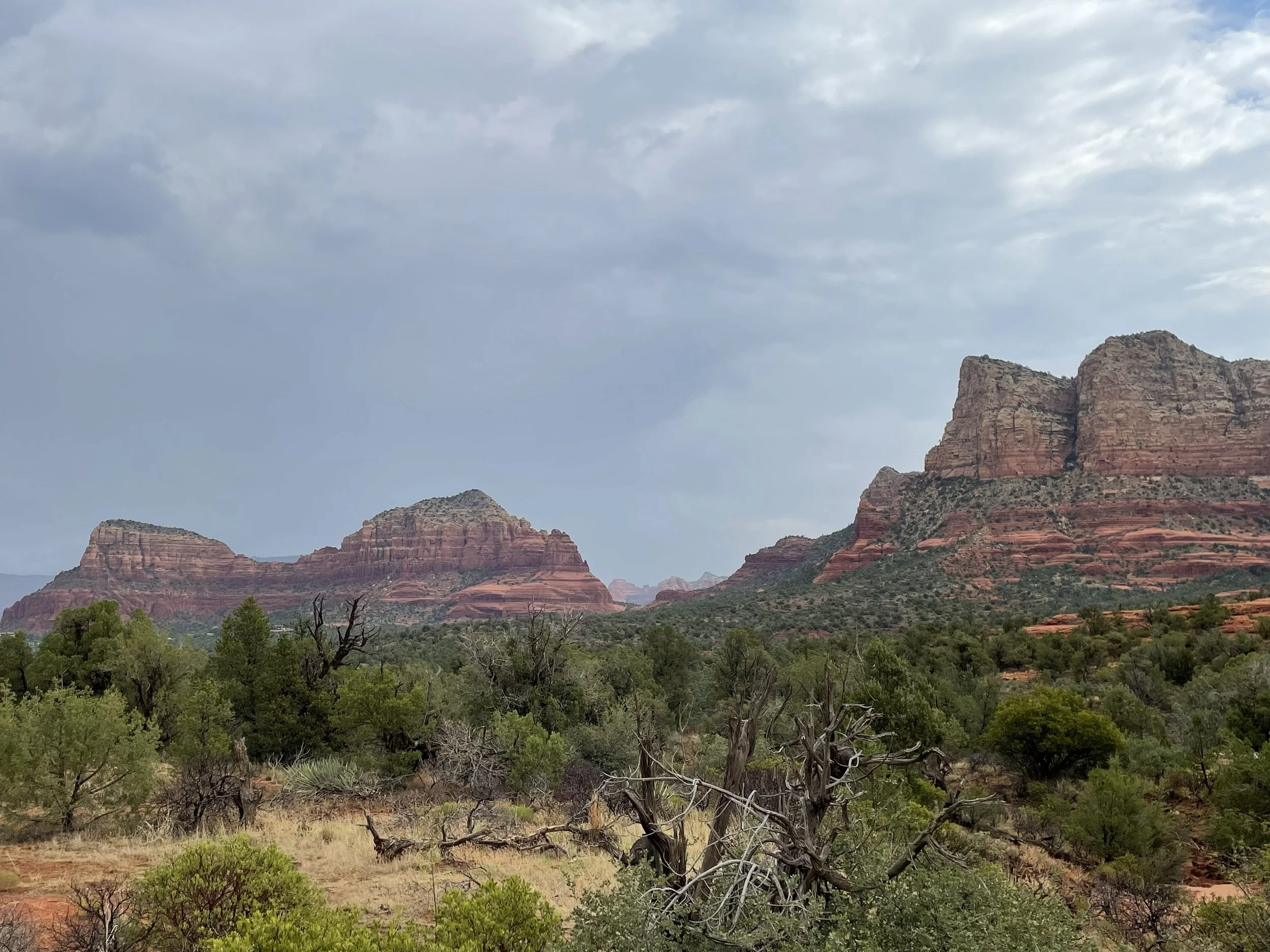 A wide landscape of Sedona red rock formations under a moody sky with desert scrub in the foreground, the open horizon beyond the spreadsheet questions.