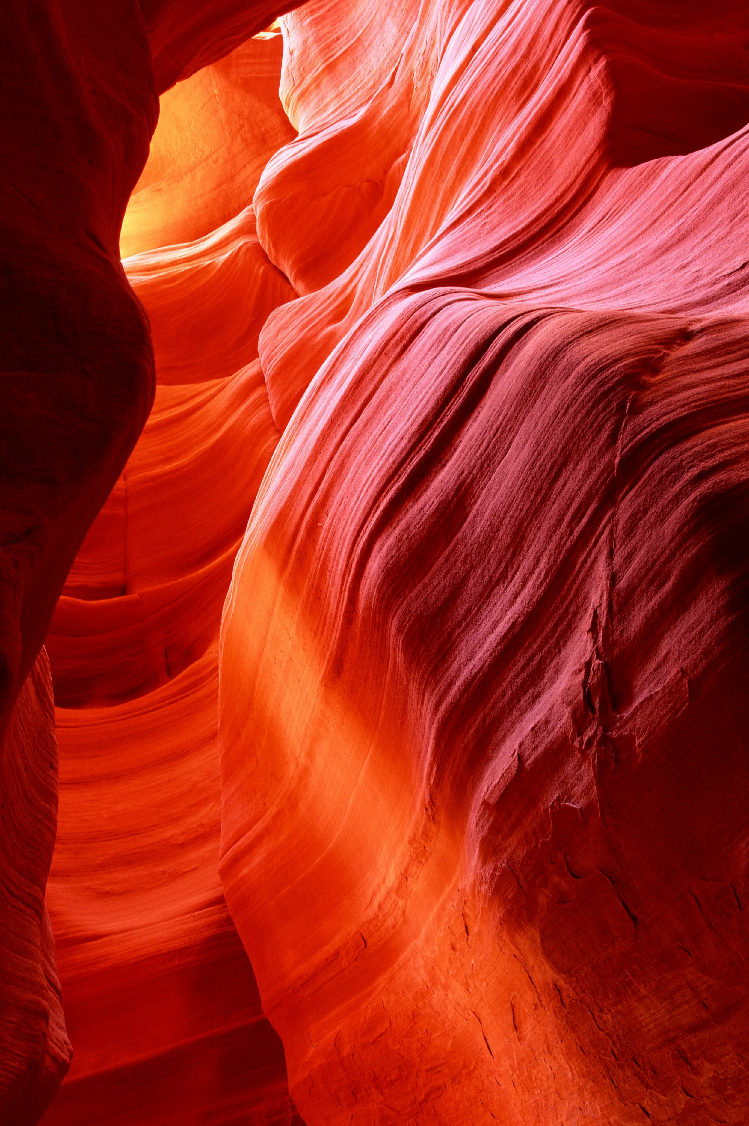 Narrow slot canyon with smooth, layered red and orange sandstone walls.