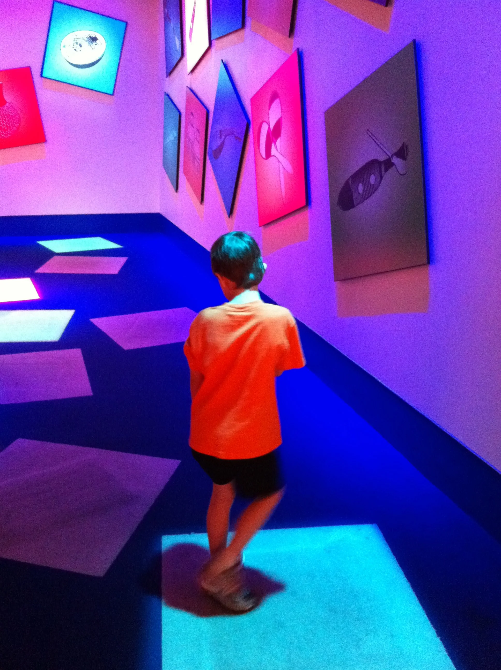 A six‑year‑old child exploring a colorful, glowing room at a theme park — a moment of pure childhood wonder.