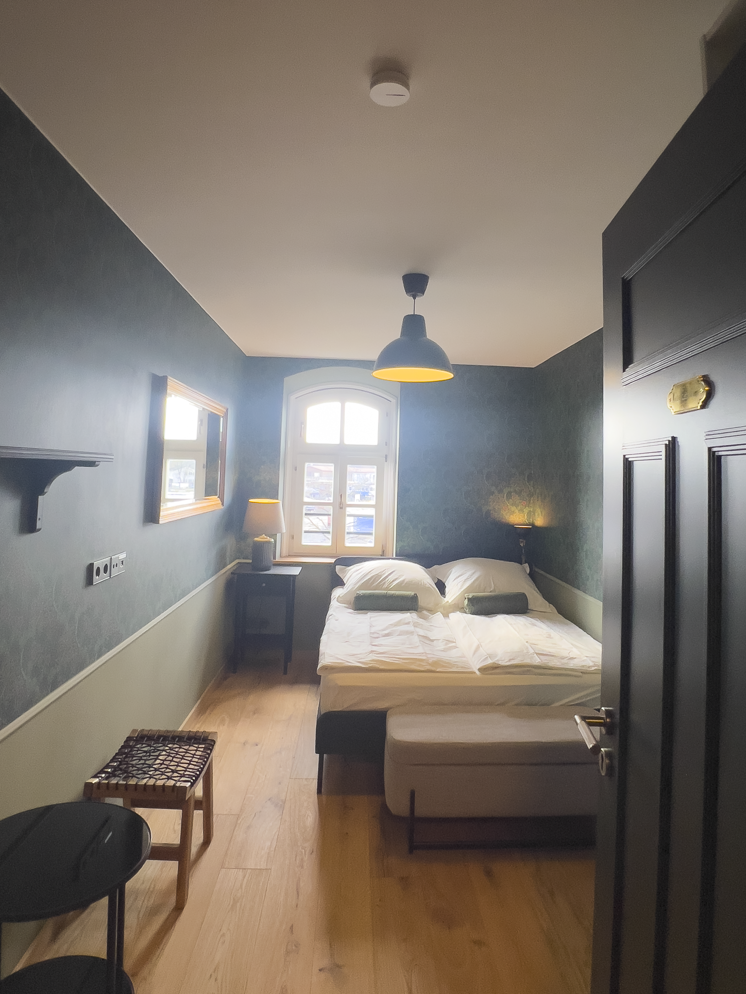 Anischt eine Gästezimmers mit dunkelgrüner Tapete und Doppelbett