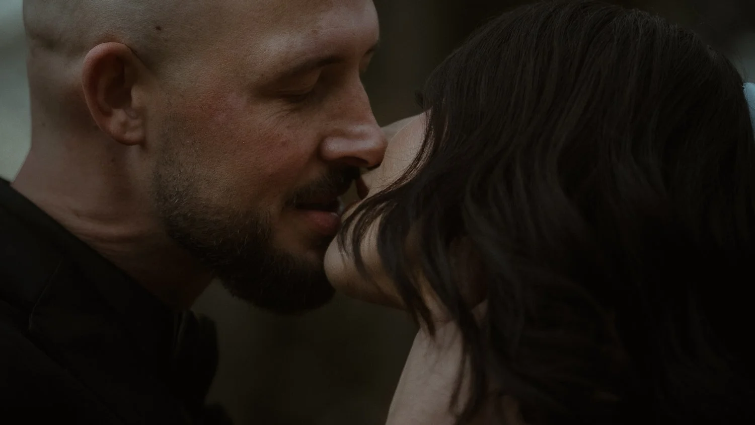 A close-up of a man and woman about to kiss, with their faces very close and eyes closed.