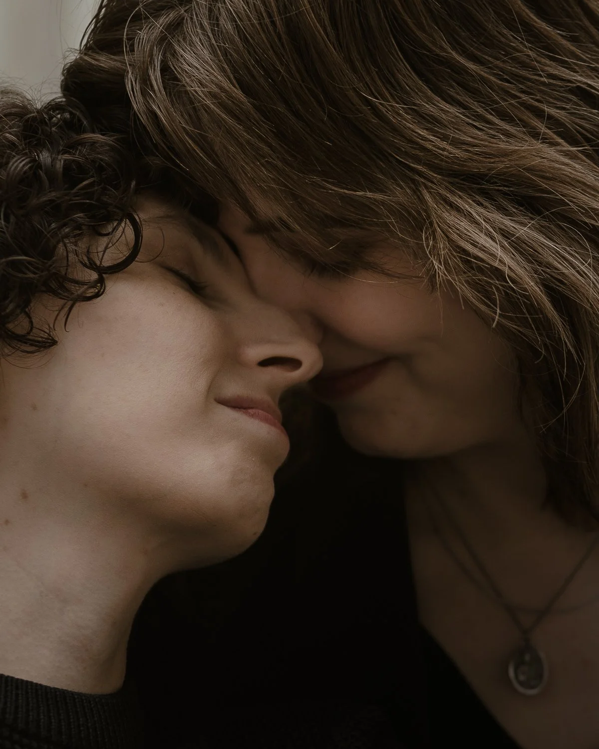 Two women with their foreheads touching, eyes closed, sharing an intimate moment.