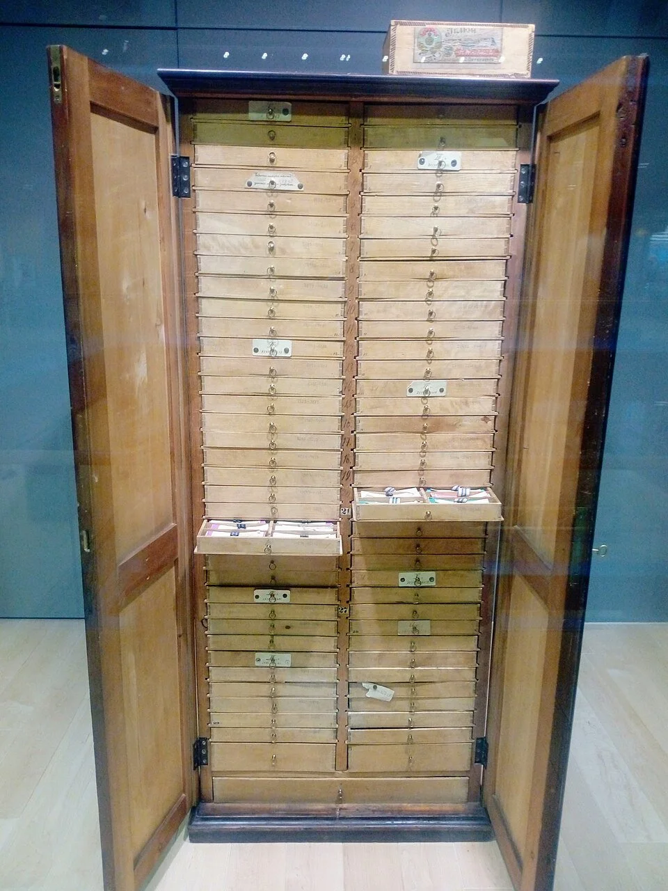 Ein voll ausgestatteter Holzbriefkasten mit vielen kleine Fächern, ein oben und zwei kleine Fächer in der Tür. Das Fach auf der linken Seite ist offen, und es sind einige Briefe darin.