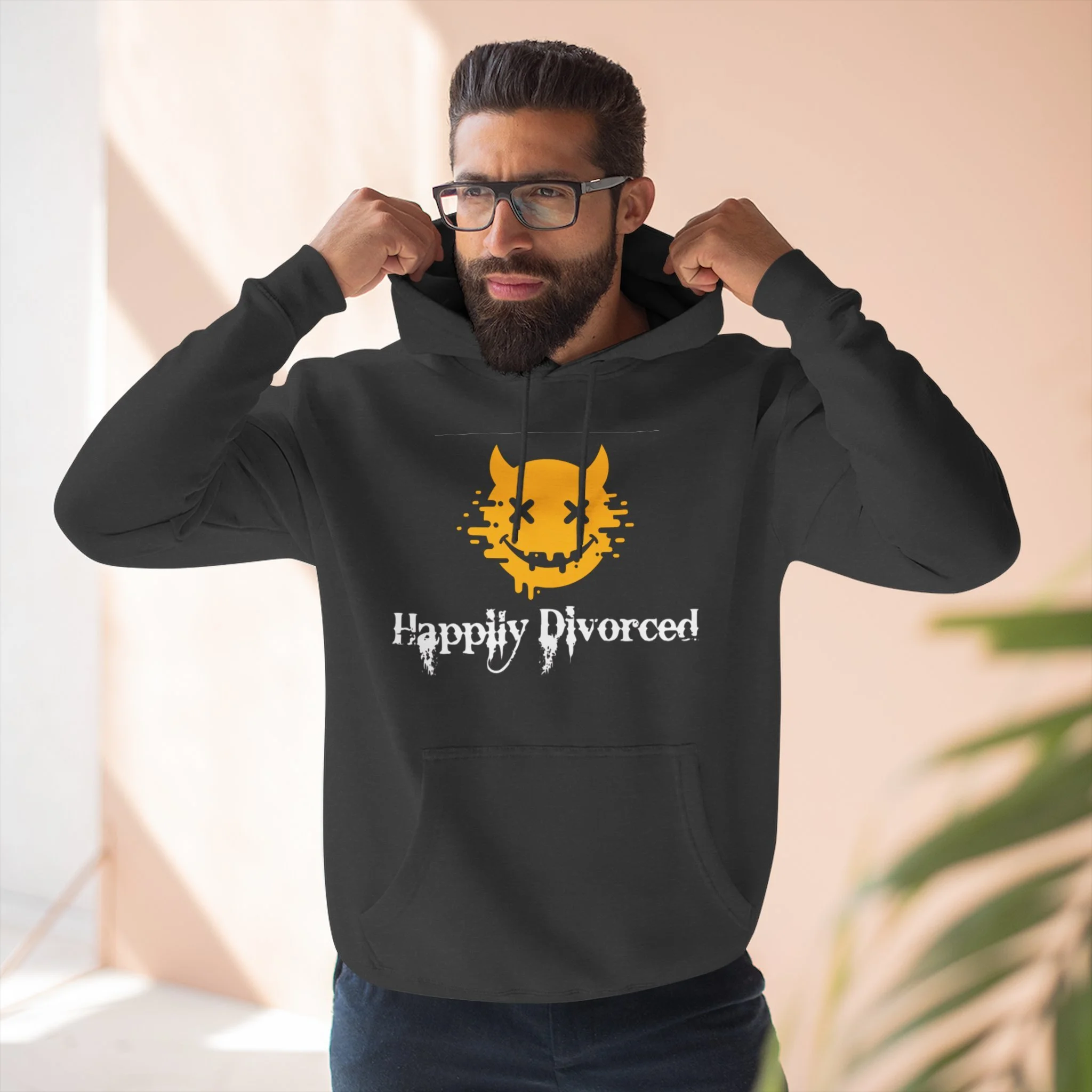 A man wearing glasses and a black hoodie with a yellow devil face graphic and the text 'Happily Divorced'.