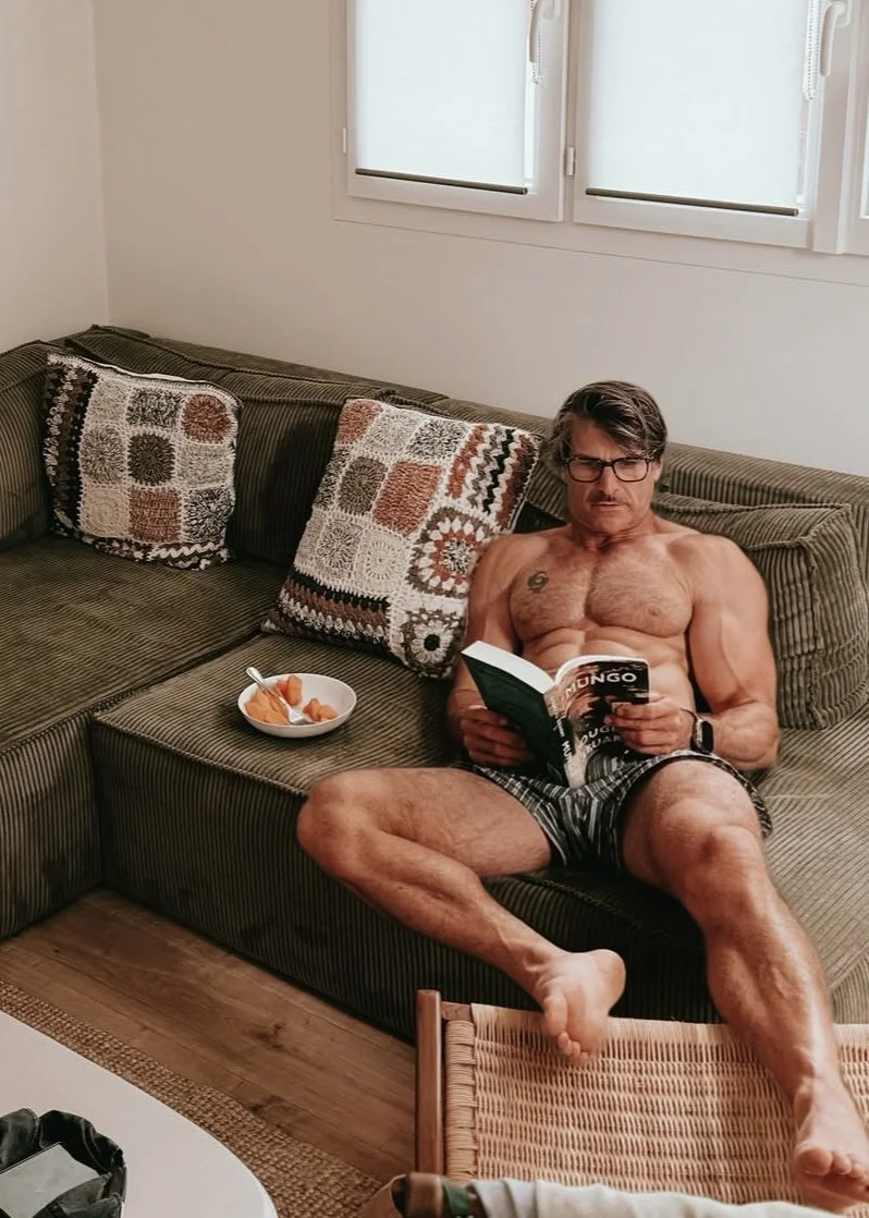 Niel relaxing on the sofa reading and wearing boxers
