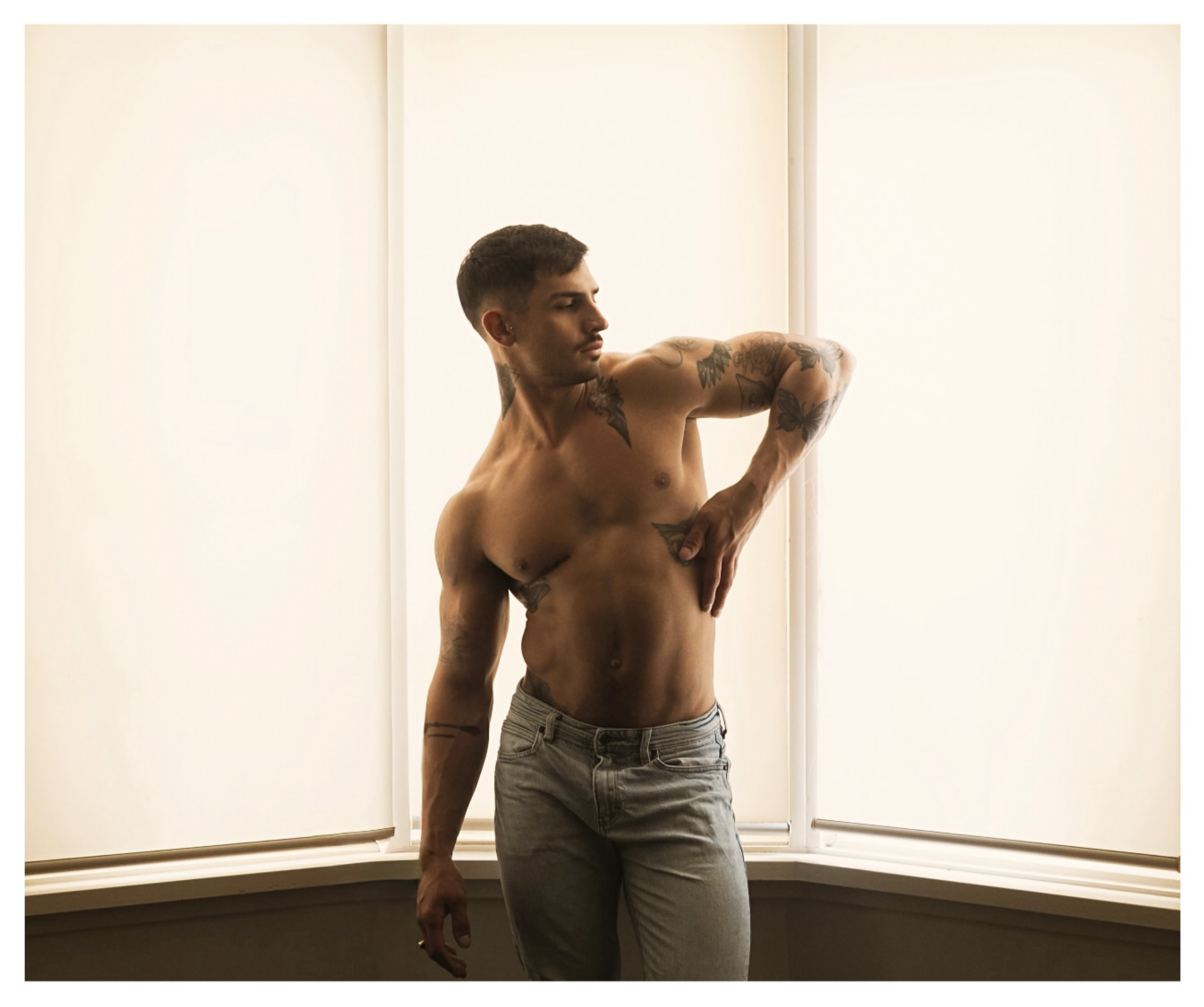 Manuel posing shirtless in a counterlight