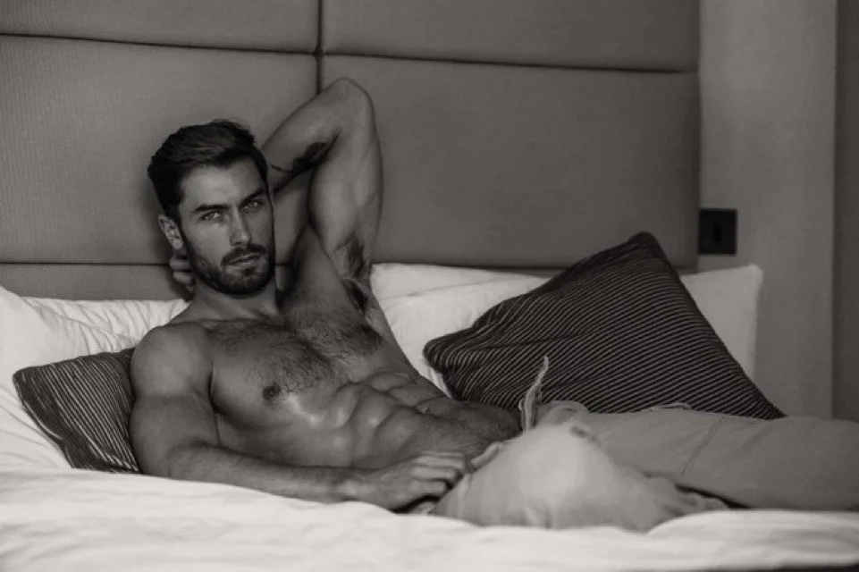 Craig Marks poses shirtless on a bed