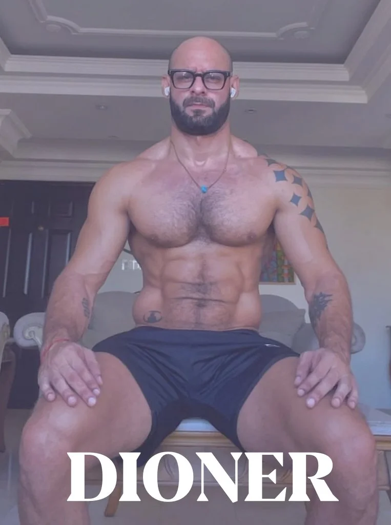 A muscular, shirtless man with tattoos and glasses sitting indoors with the word 'DIONER' written at the bottom.