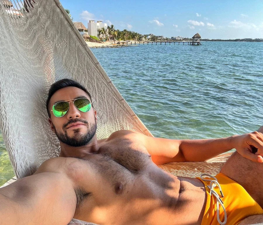 Alejandro sunbathing in a hammock on the beach