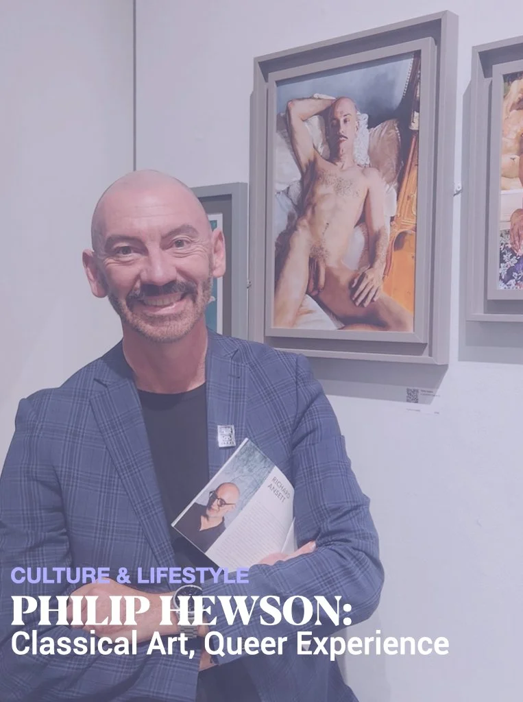 A man in a plaid blazer smiling and holding a brochure at an art exhibit. Behind him, there is a large framed painting of a nude person in a reclining pose. The text overlay reads: 'Culture & Lifestyle, Philip Hewson: Classical Art, Queer Experience.'