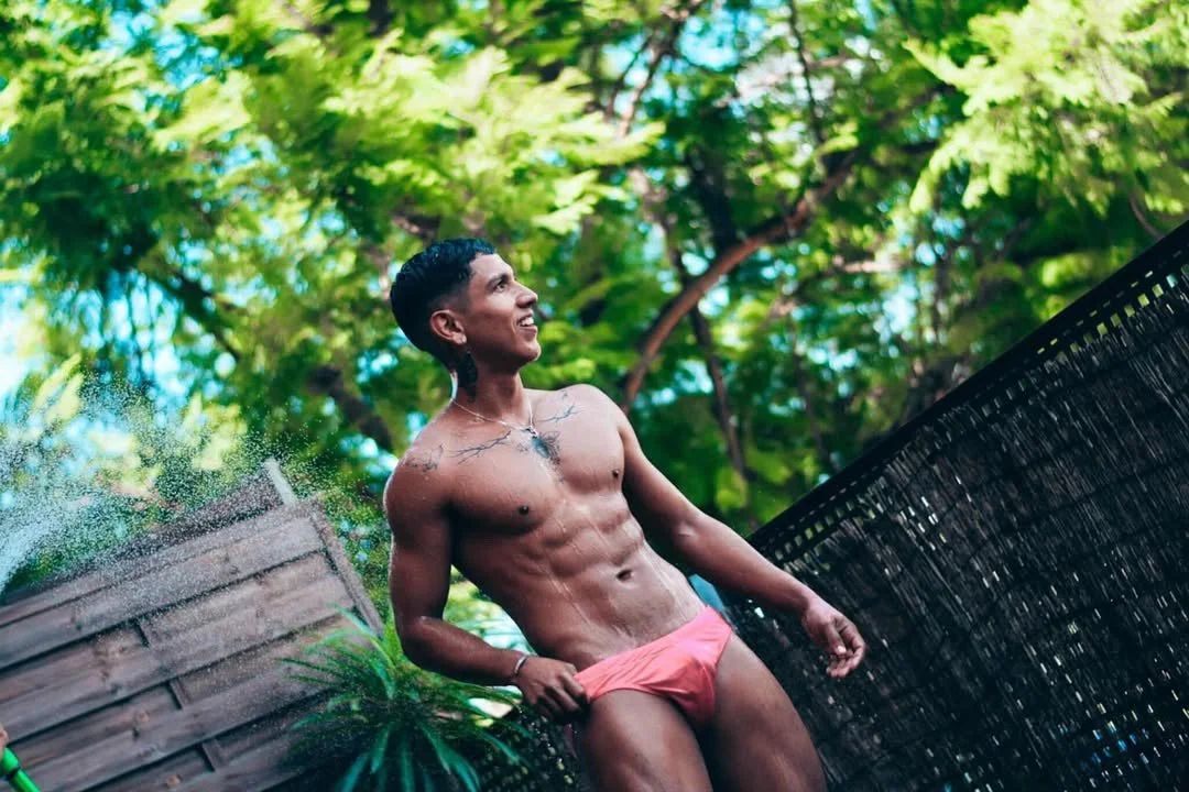 Jeferson stands outside after a shower, wearing swimwear