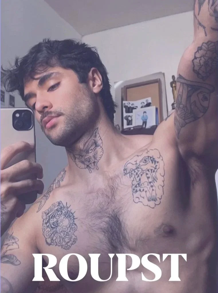 A shirtless man with dark hair and tattooed chest and arms taking a selfie in a mirror, with the word "ROUPST" overlayed at the bottom.