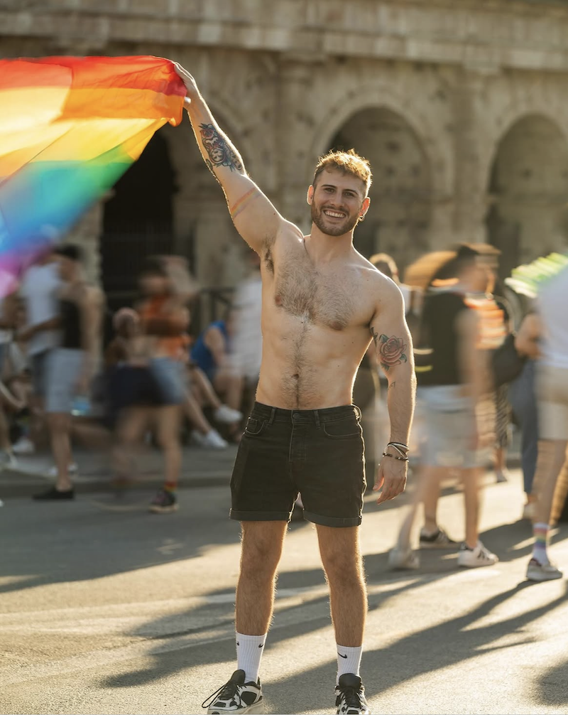 @danielecoletta in Rome Pride, shirtless, waving a pride flag Photo by @iacopocarinciph