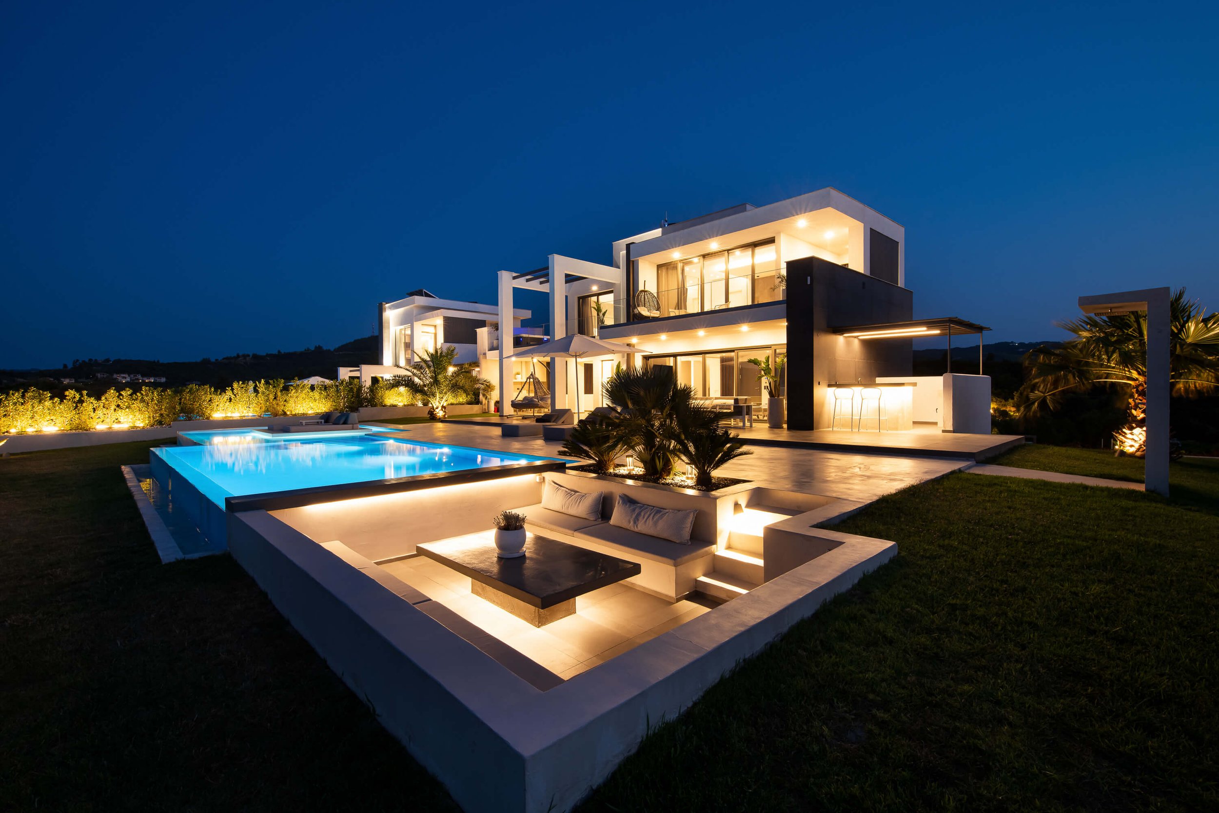 Nighttime view of Antonio Villa private infinity pool and lush outdoor space Halkidiki