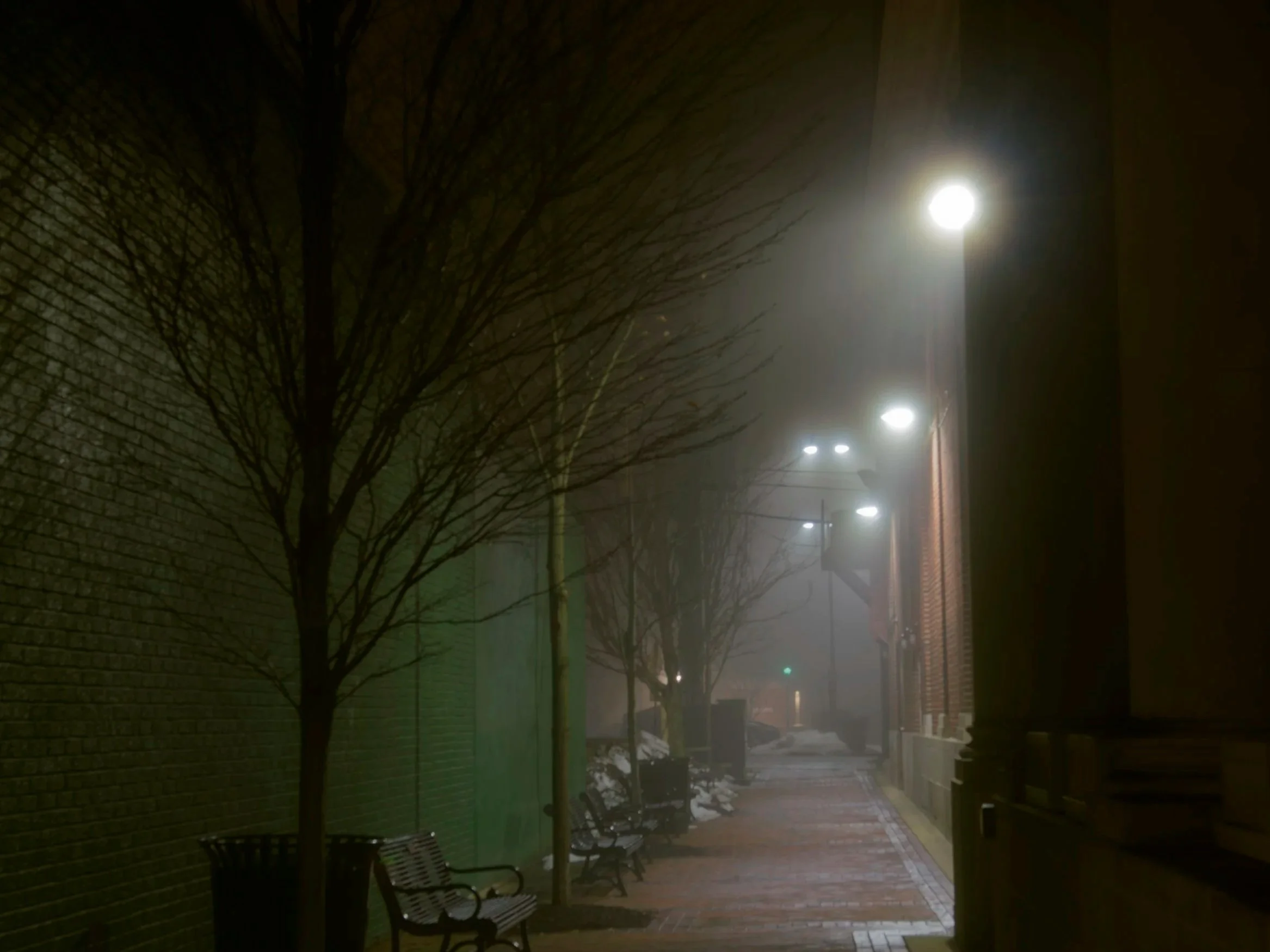 Alley way at night that is lit and has fog.