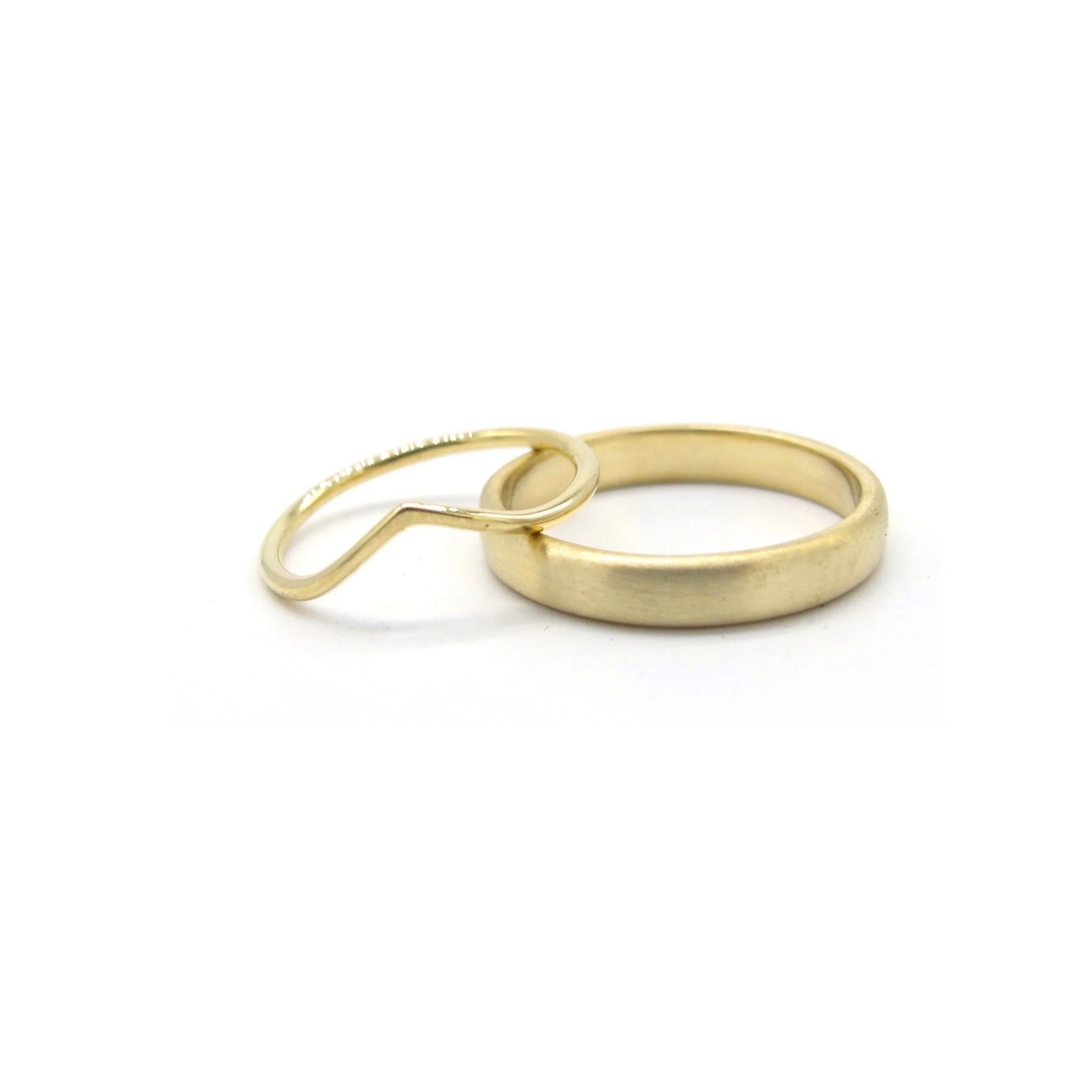 Two gold rings, one plain and one with a small loop, on a white background.