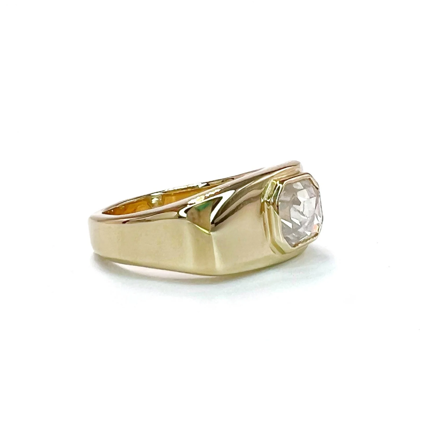 Gold ring with a large, round, clear gemstone on a white background.