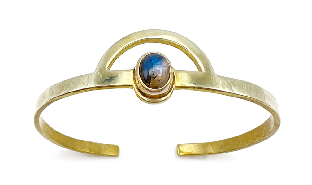 Gold bracelet with an open design and a small oval dark gemstone in the center.