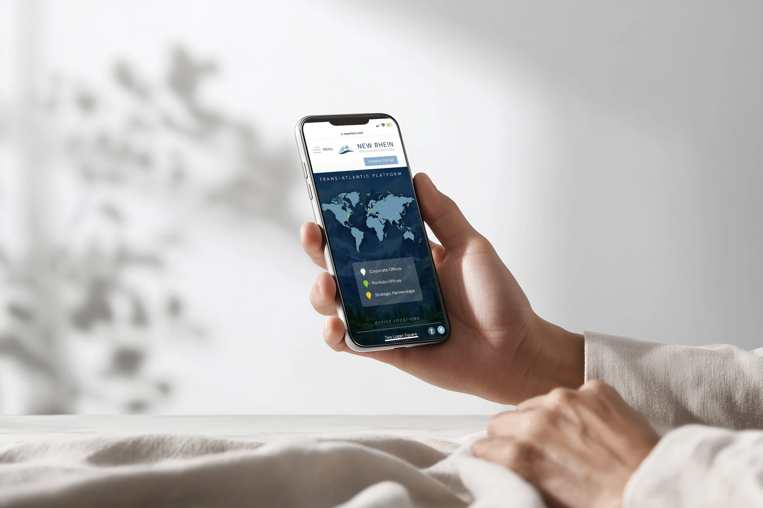 Person holding a smartphone displaying a world map and office locations on a website.