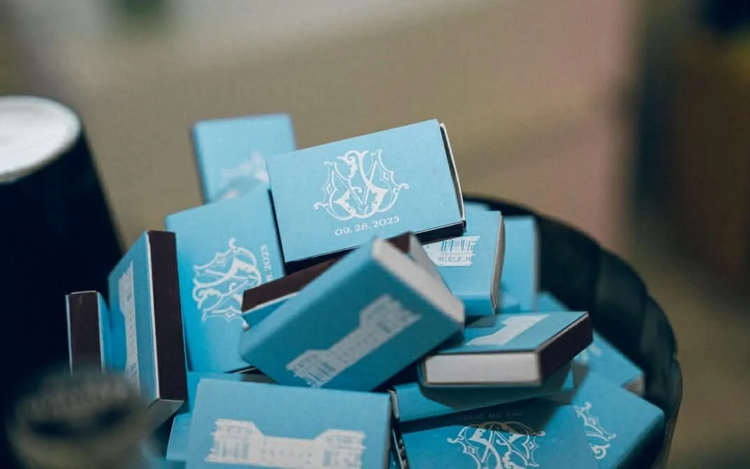 A basket filled with small blue boxes, some showing a monogram and a date, with a black object to the side.