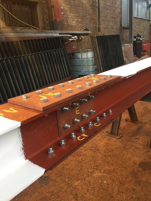 Close-up of a structural steel beam splice with bolted flange and web plates.