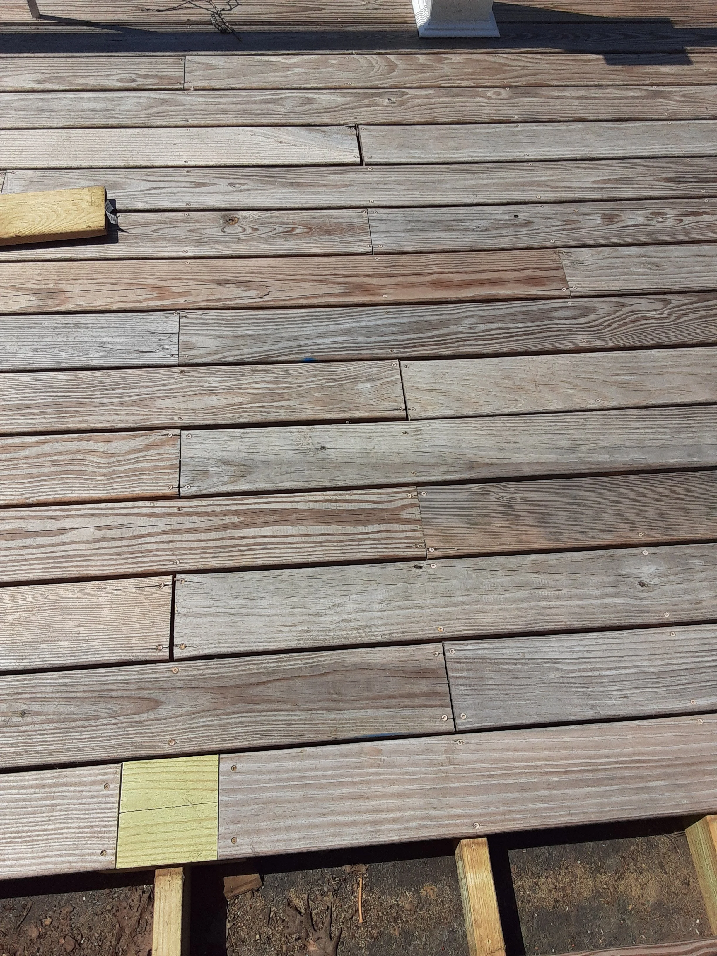 Close-up of a wooden deck under construction, with planks and some support beams visible.