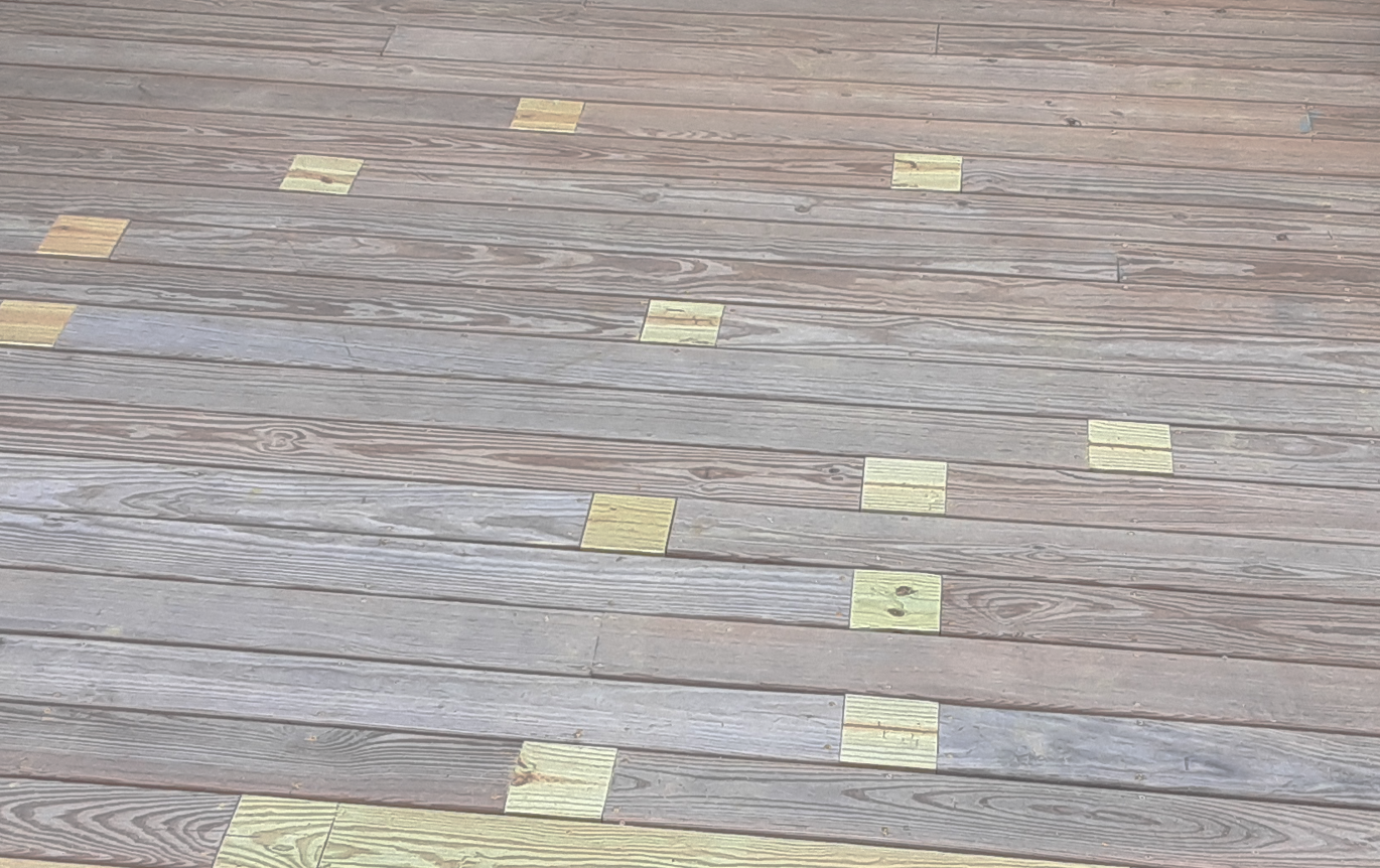 Wooden deck with scattered yellow and brown tiles.