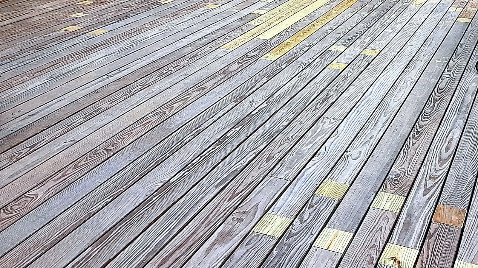 Close-up of wooden floorboards with some yellow and one orange tiles.