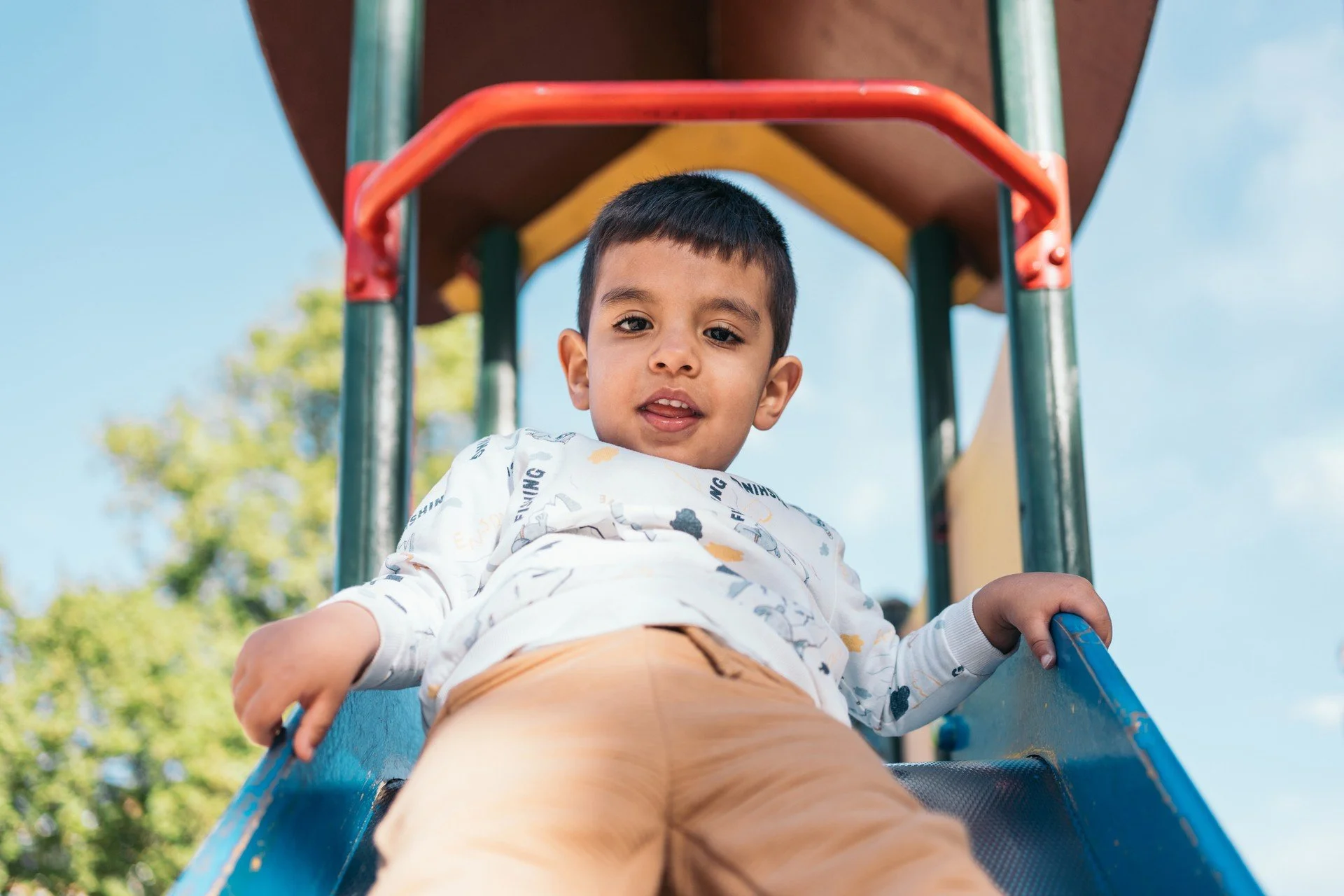 Toddler boy smiling on a slide