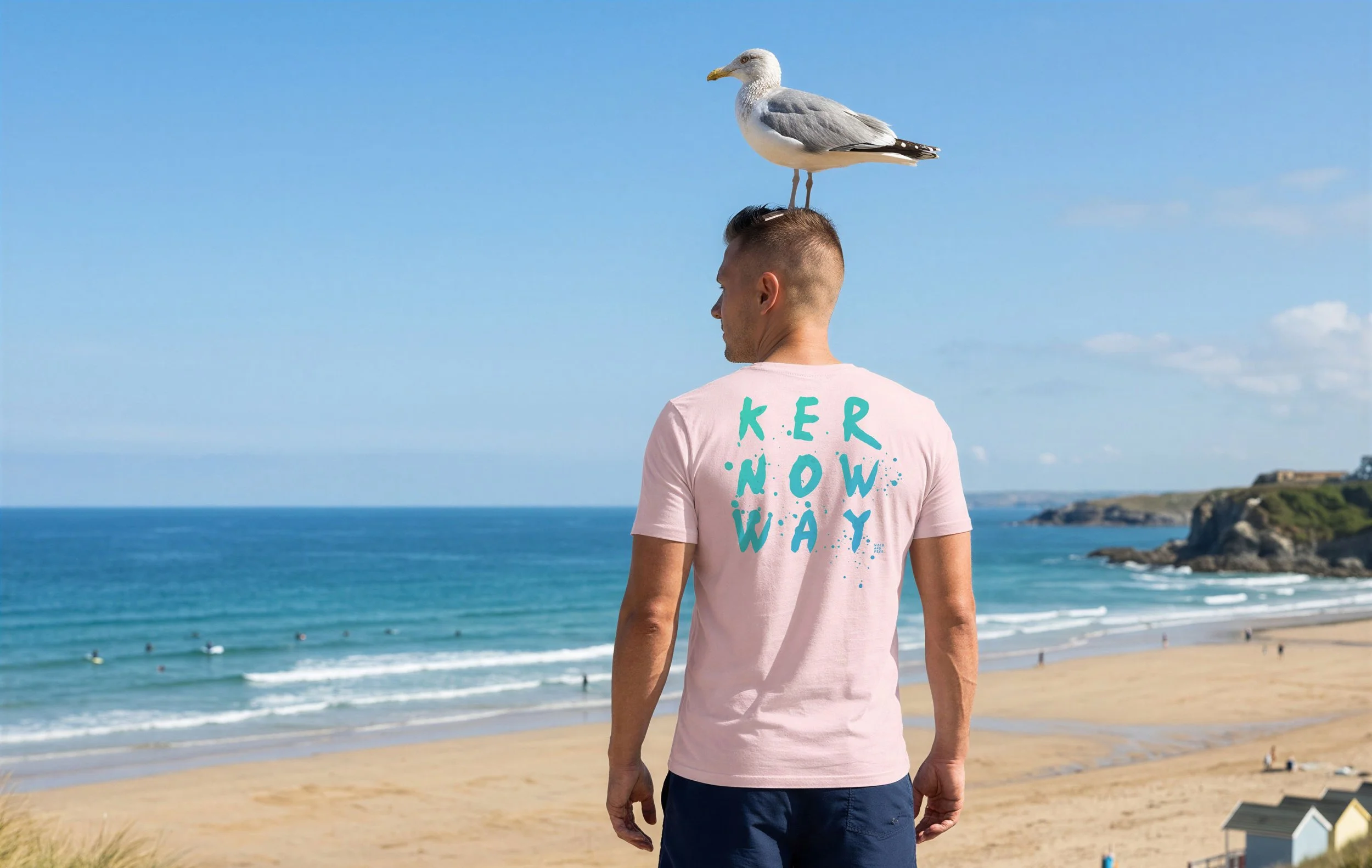 A man stands on a beach with his back to the camera, wearing a pink T-shirt that says "K.E.R. NOW WAY" in turquoise letters. There is a seagull perched on his head, and the ocean and sky are in the background.