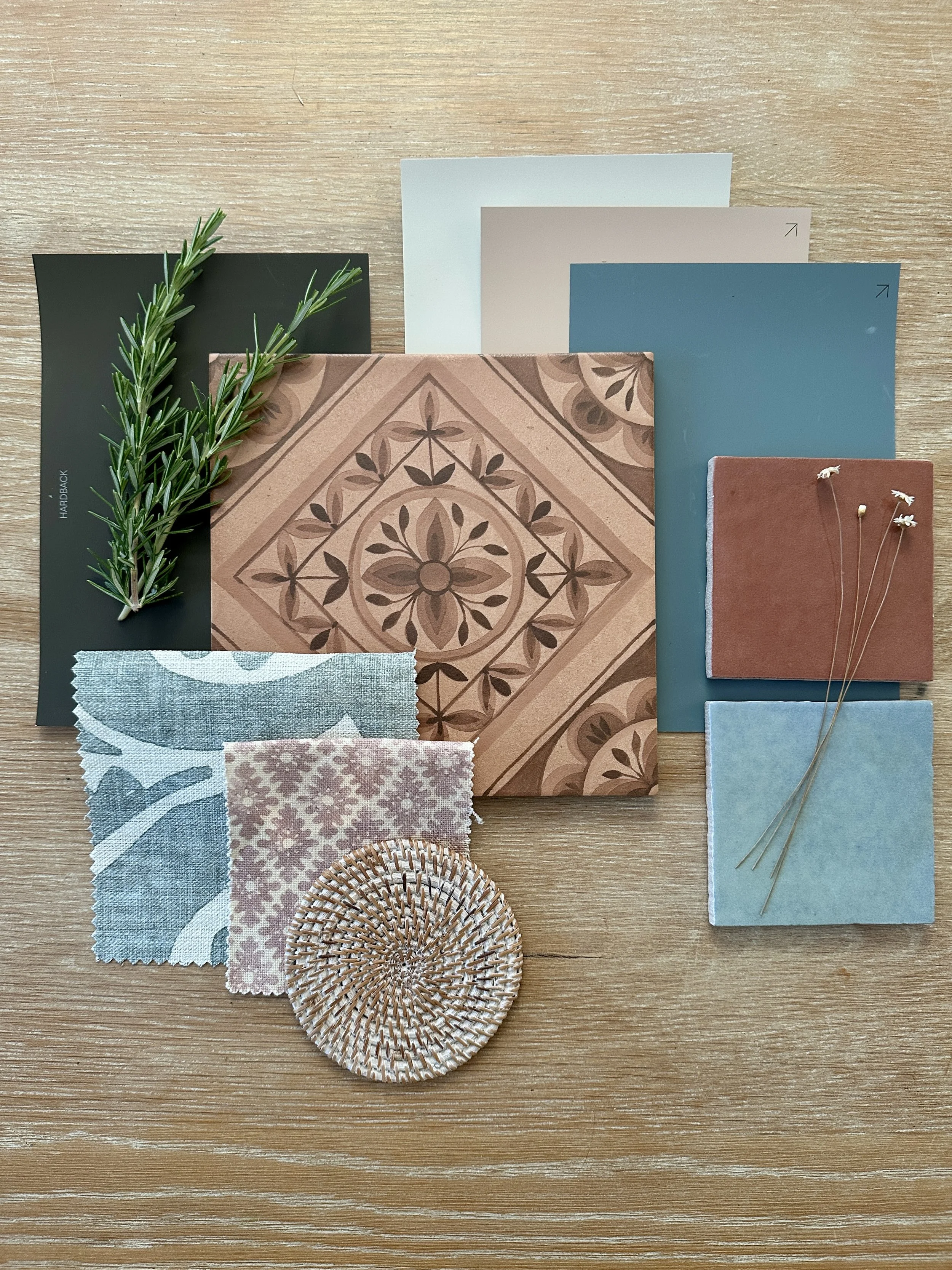 A flat lay of fabric swatches, paint colours, decorative tiles on a wooden surface.
