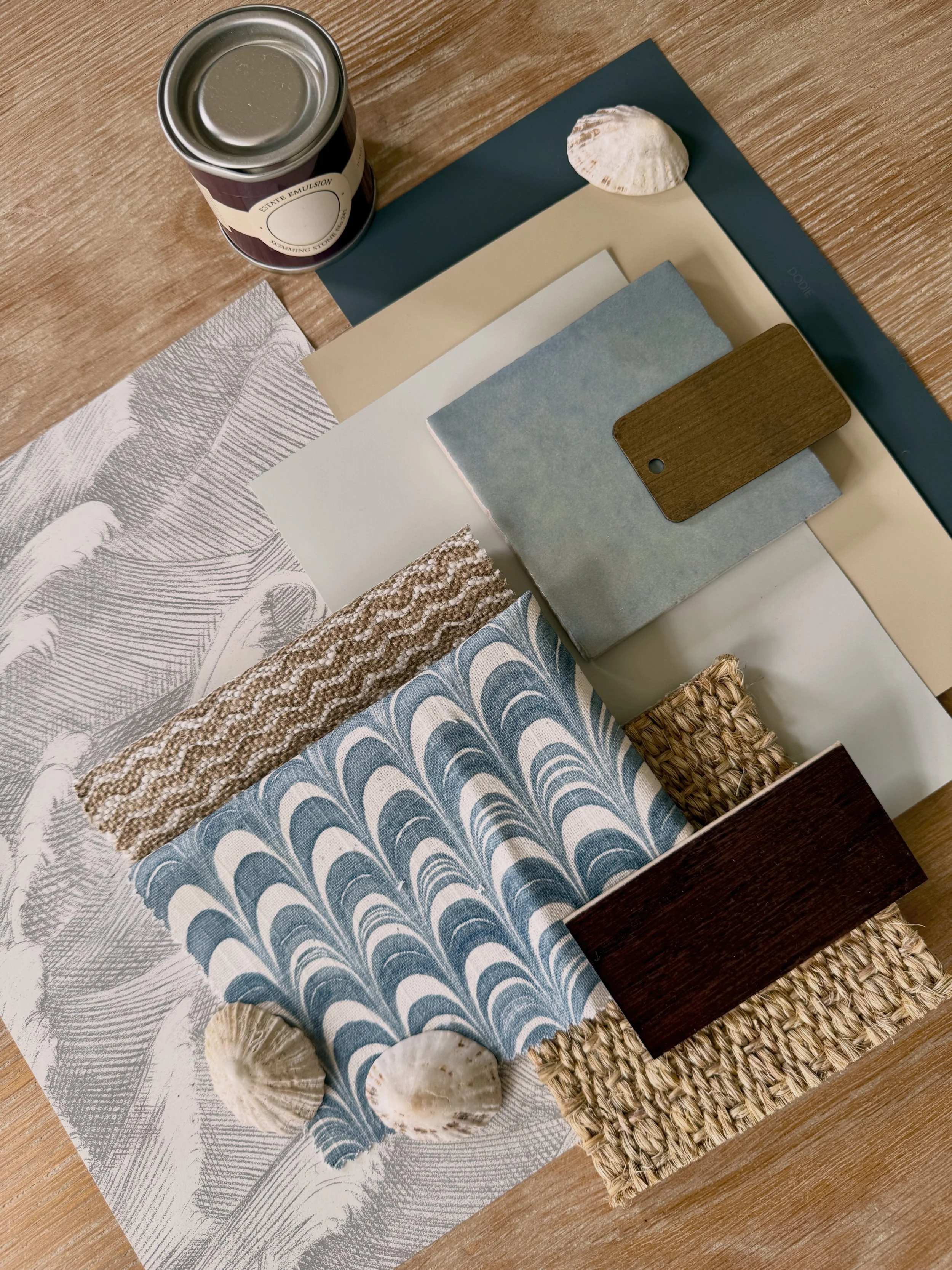 Sample displaying various fabric swatches, a shell, a can of paint, and a wooden sample on a wooden surface.