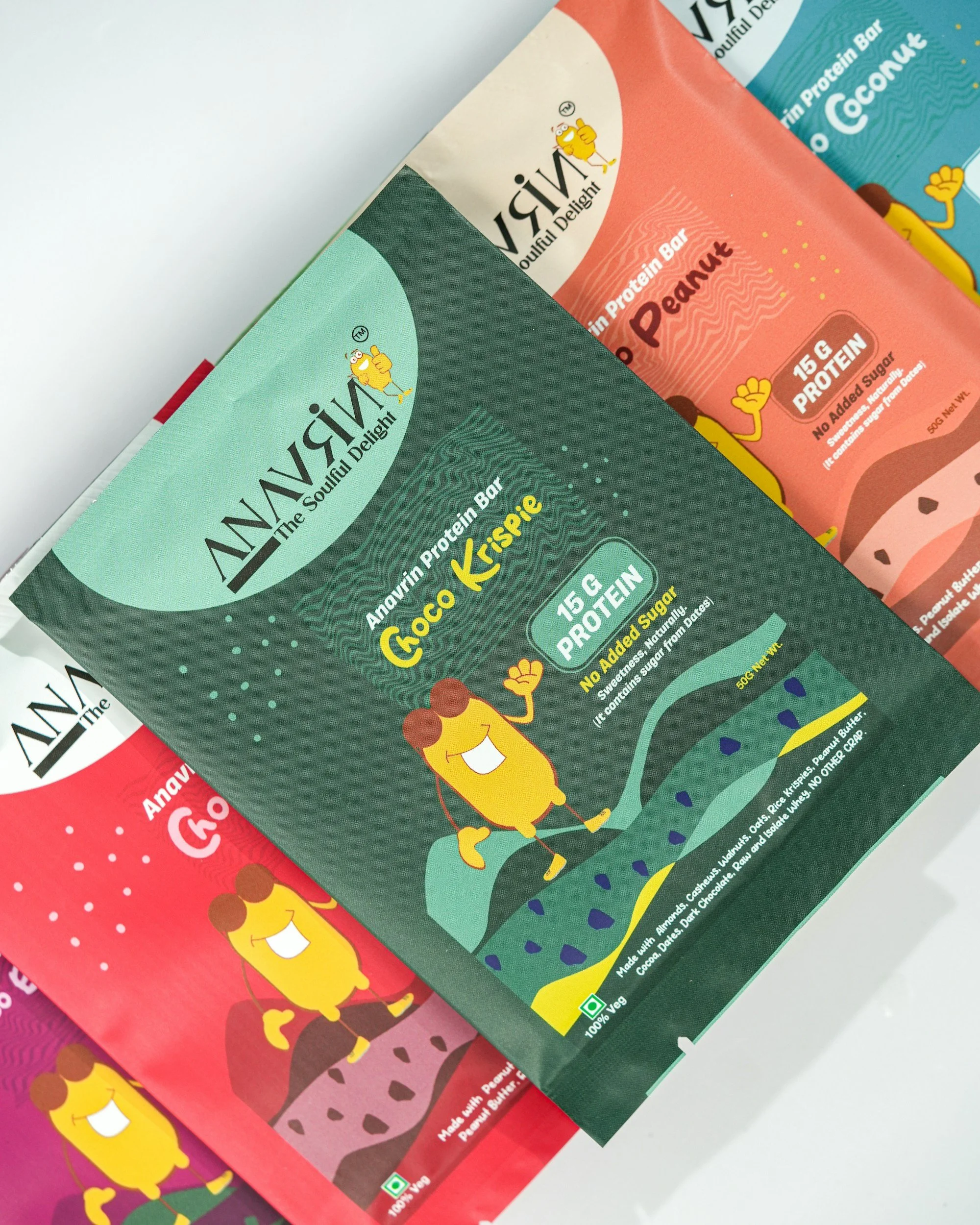 Paquete de barras de proteína Anavive con sabor a galleta Cripsie, en colores verde y rosa, con ilustraciones de un personaje animado feliz y un fondo colorido.