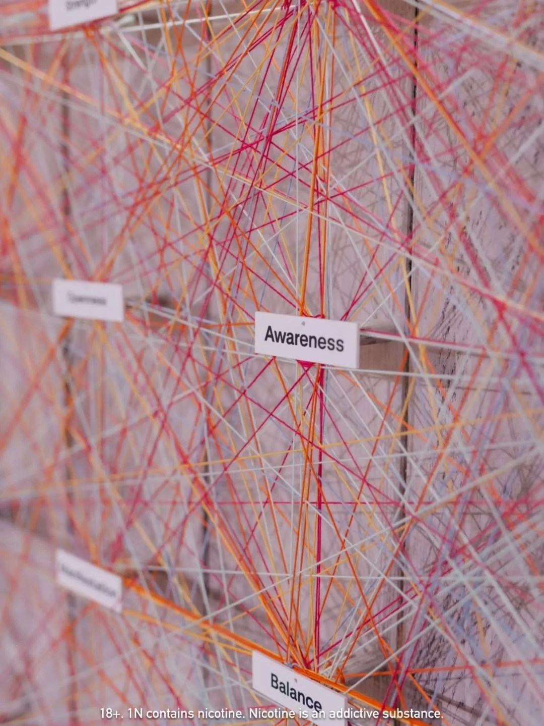 A colorful honeycomb art installation with interconnected multicolored sticks and labels such as "Awareness" and "Balance."