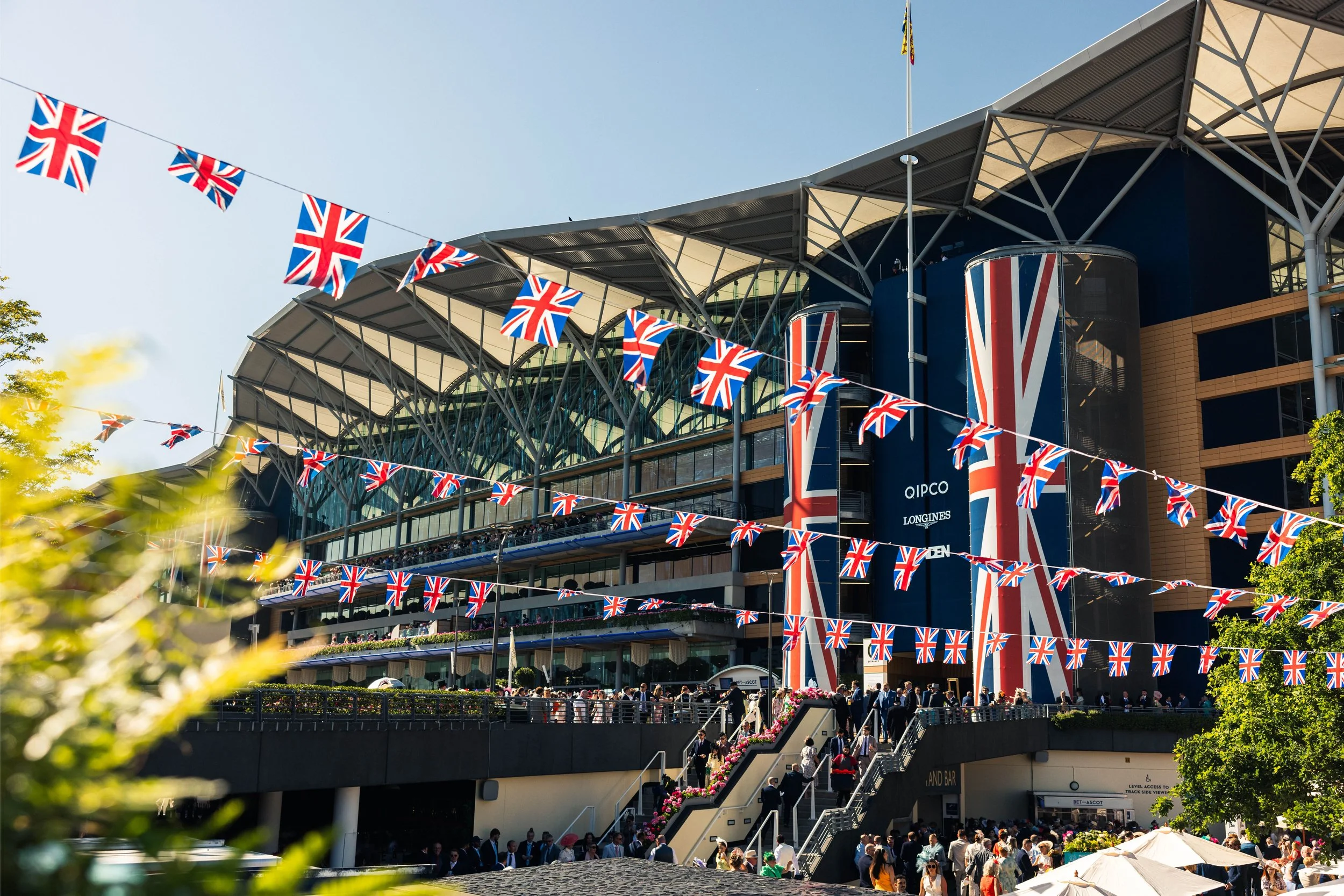 Crowd outside a modern building decorated with Union Jack flags, likely a venue for a British celebration or event.