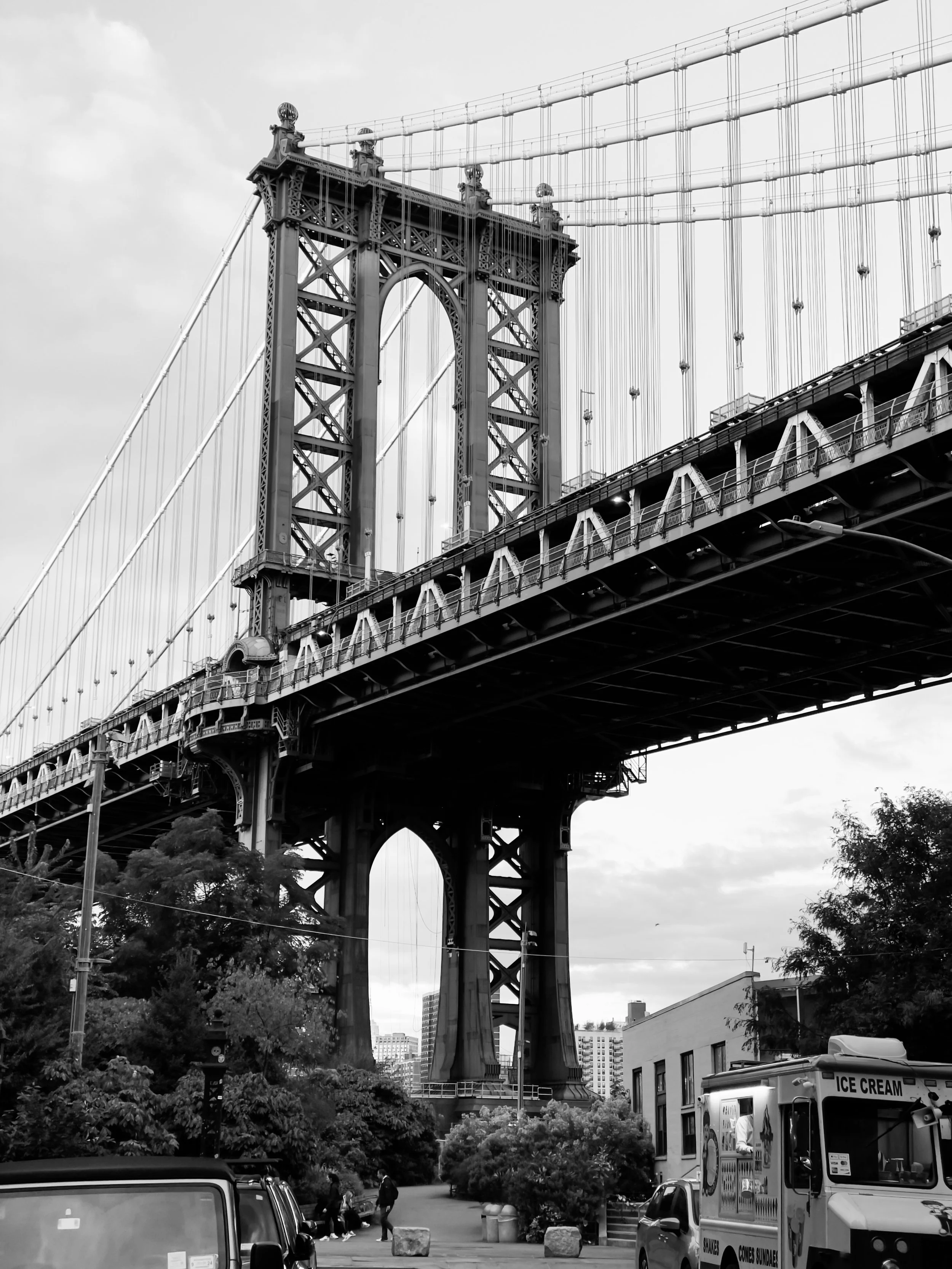 Black and white photo of the Brooklyn Bridge in New York City, showing its suspension cables and stone towers.